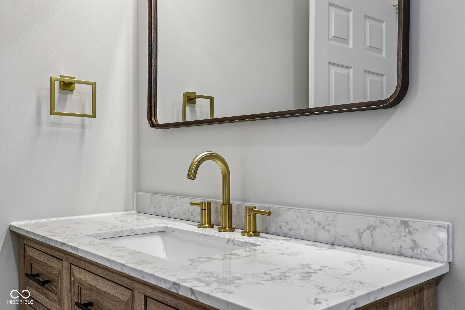 Integrated vanity with a white rectangular sink, brass-finish faucet, and a stone countertop