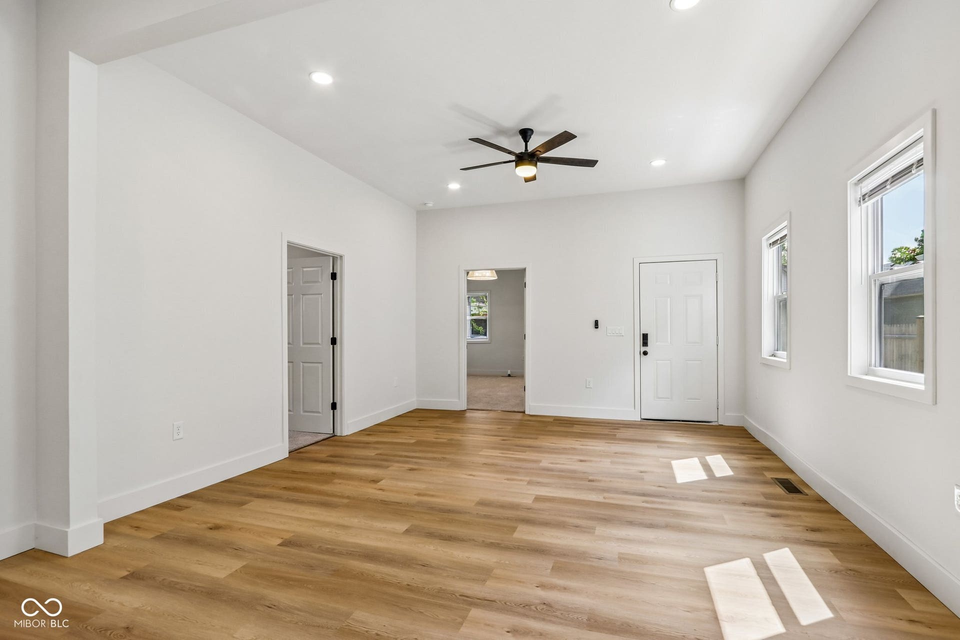 Light wood-finish flooring, recessed lighting, and a ceiling fan with integrated light