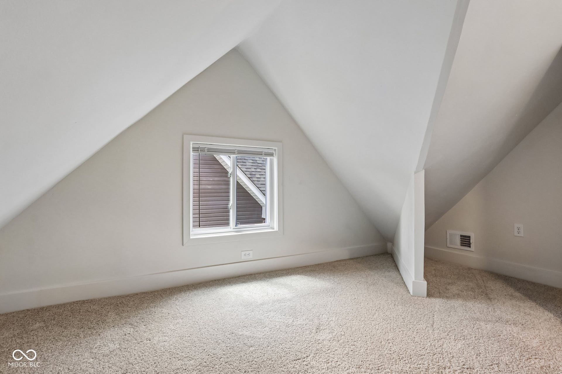 Sloped ceilings, neutral wall color, and light-toned carpeting
