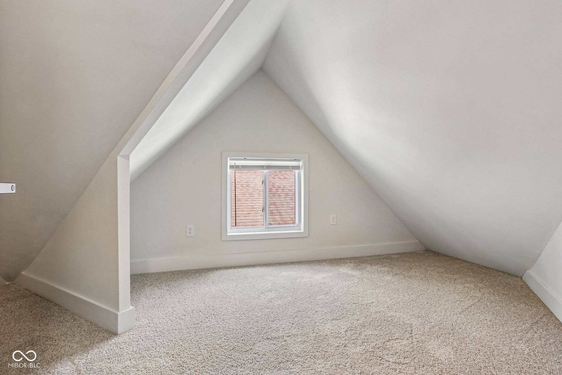 Carpeted room with sloped ceilings and a double-hung window