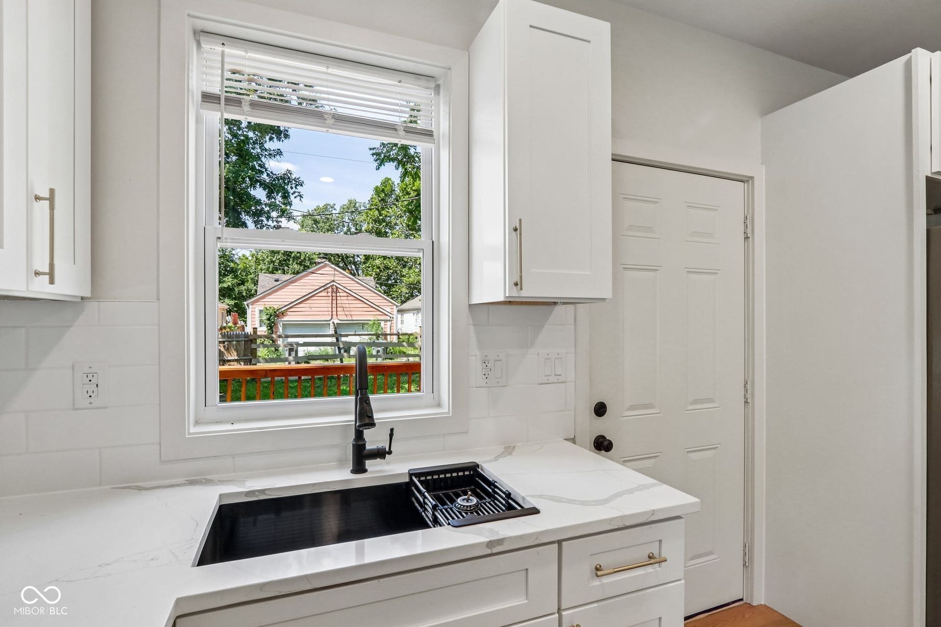White shaker-style cabinetry, a contrasting black sink with a matte black faucet, and a subway tile backsplash
