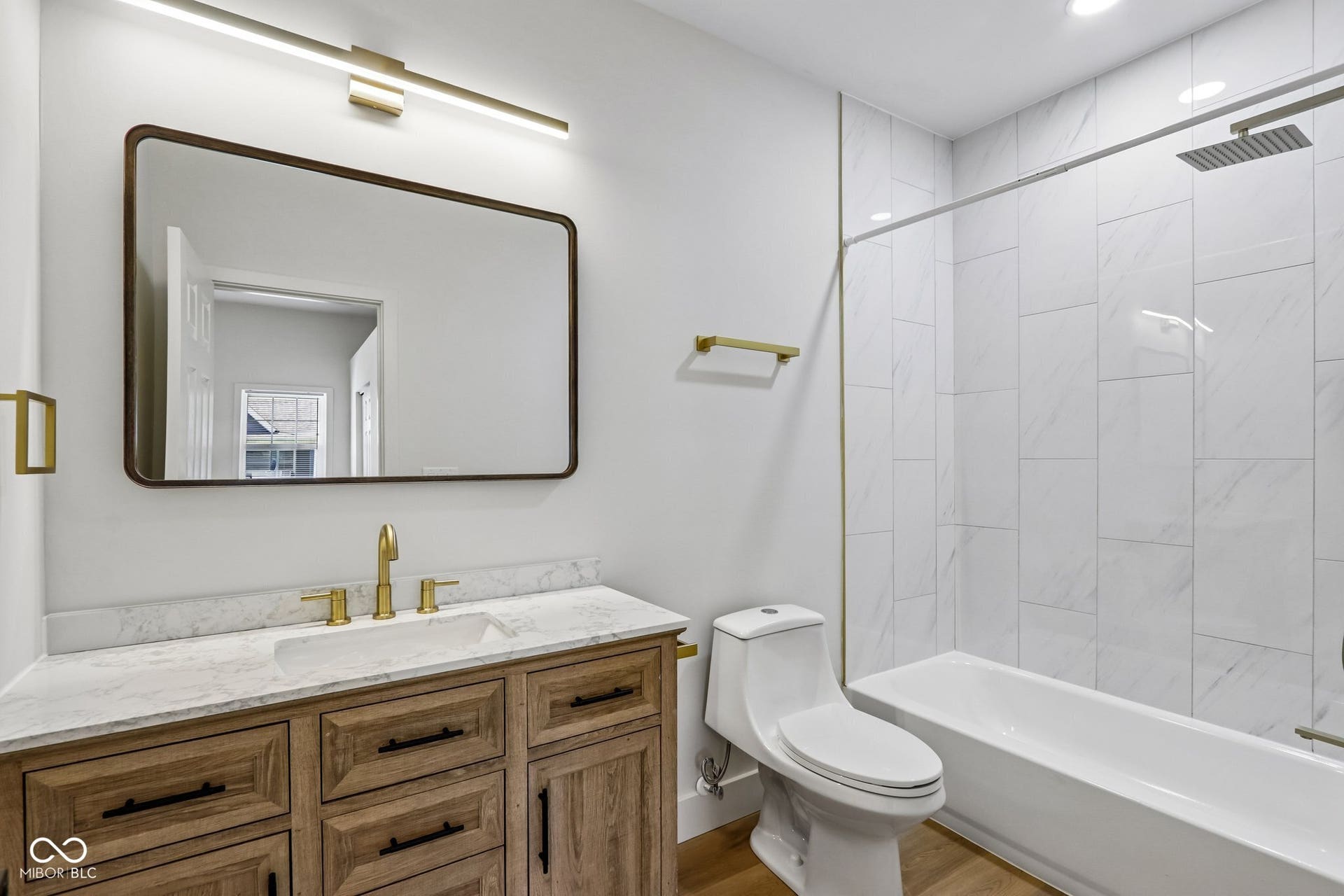 Wood-finish vanity with a rectangular undermount sink, brass faucet, and white stone countertop