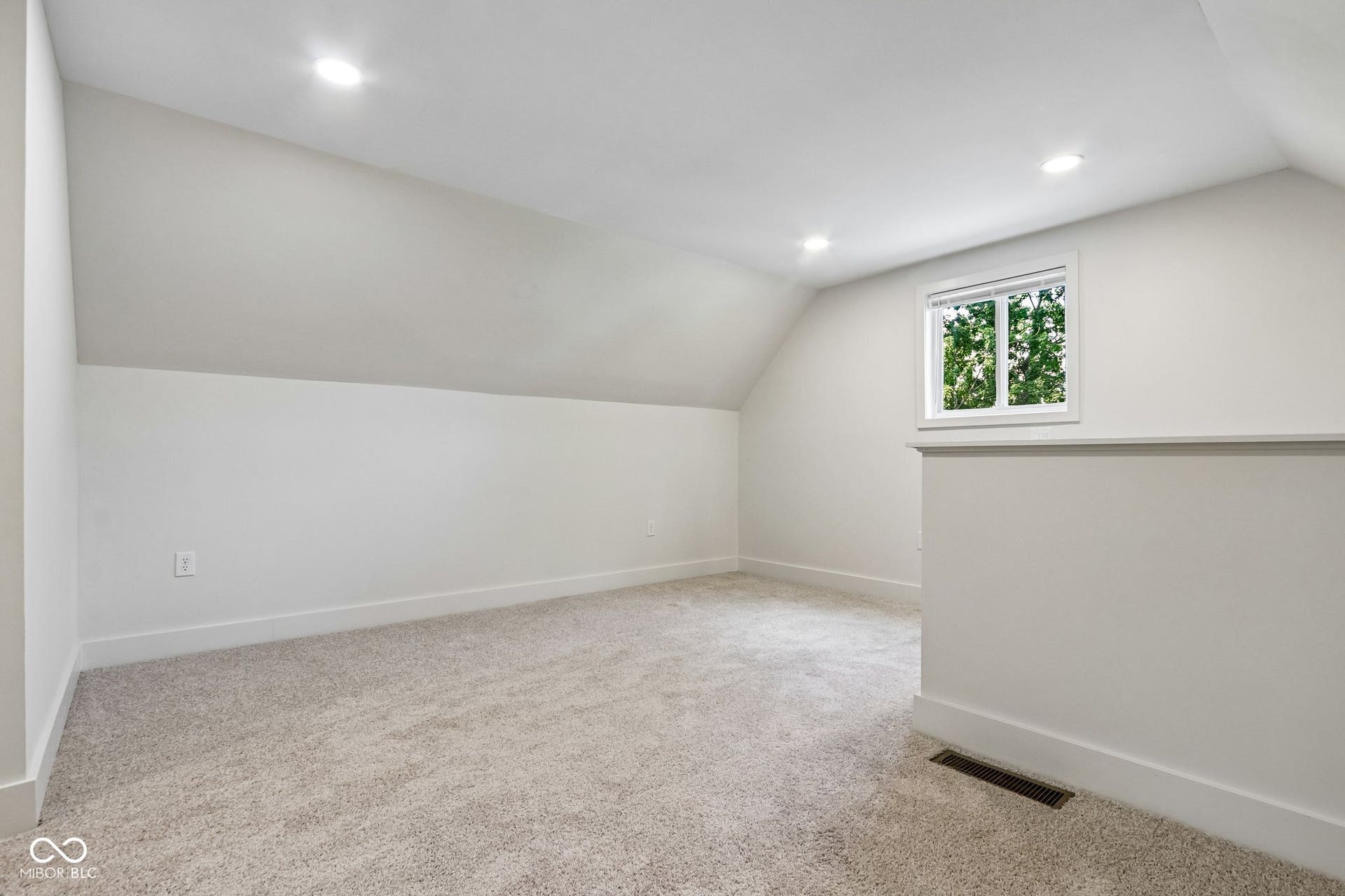 Recessed lighting, sloped ceilings, white walls, and light-colored carpeting