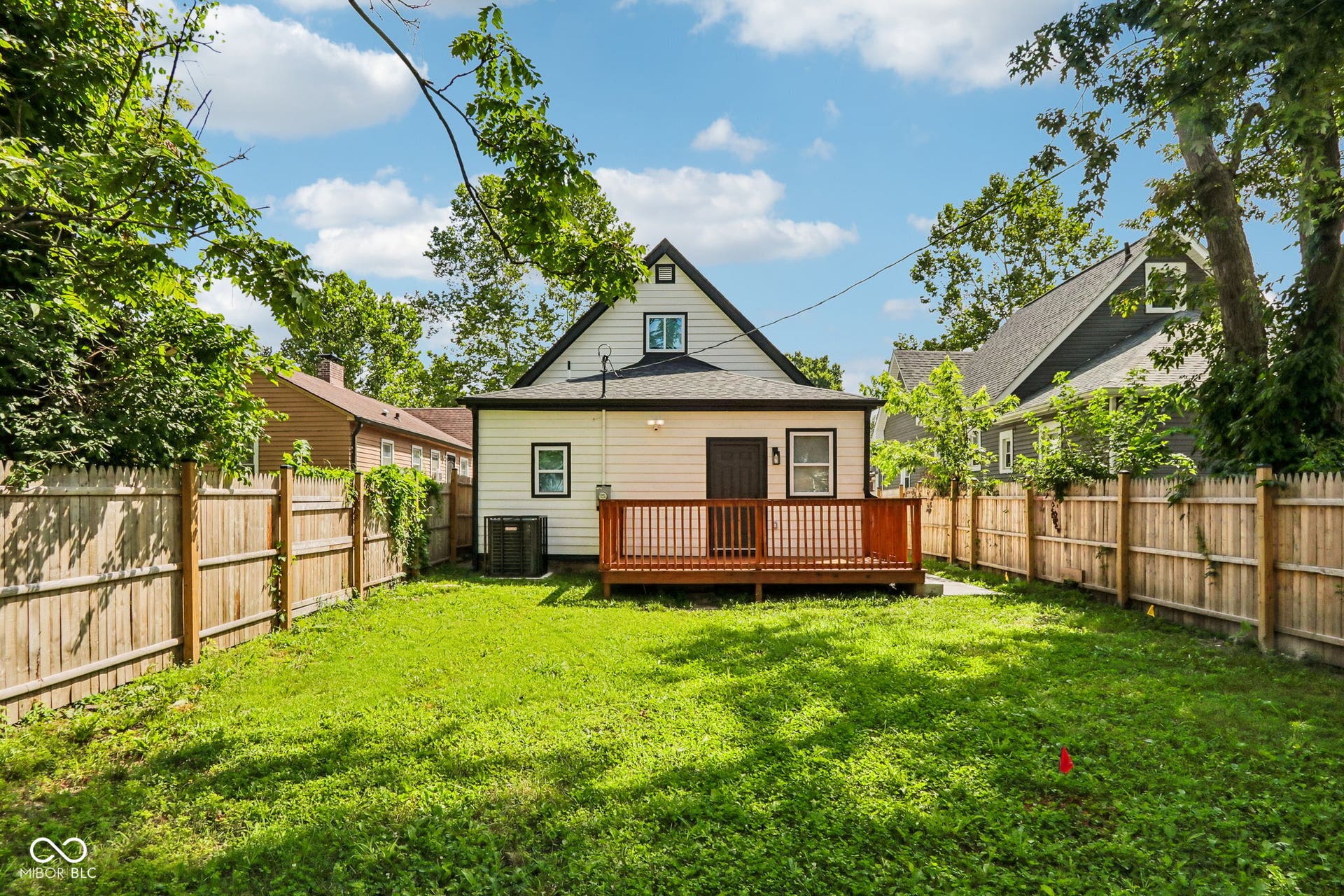 Expansive backyard featuring a wood privacy fence, a wood deck, and a white siding exterior