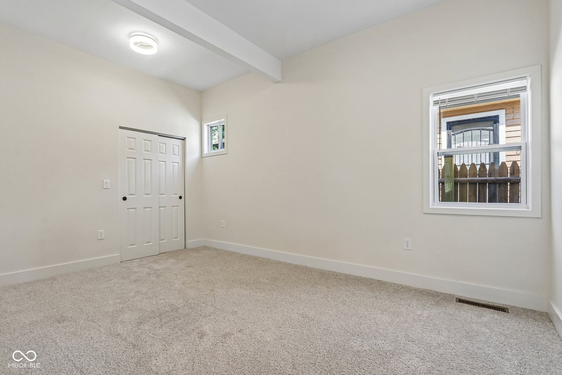 Neutral carpeting, vaulted ceiling with exposed beam, white trim, sliding closet doors, and recessed lighting