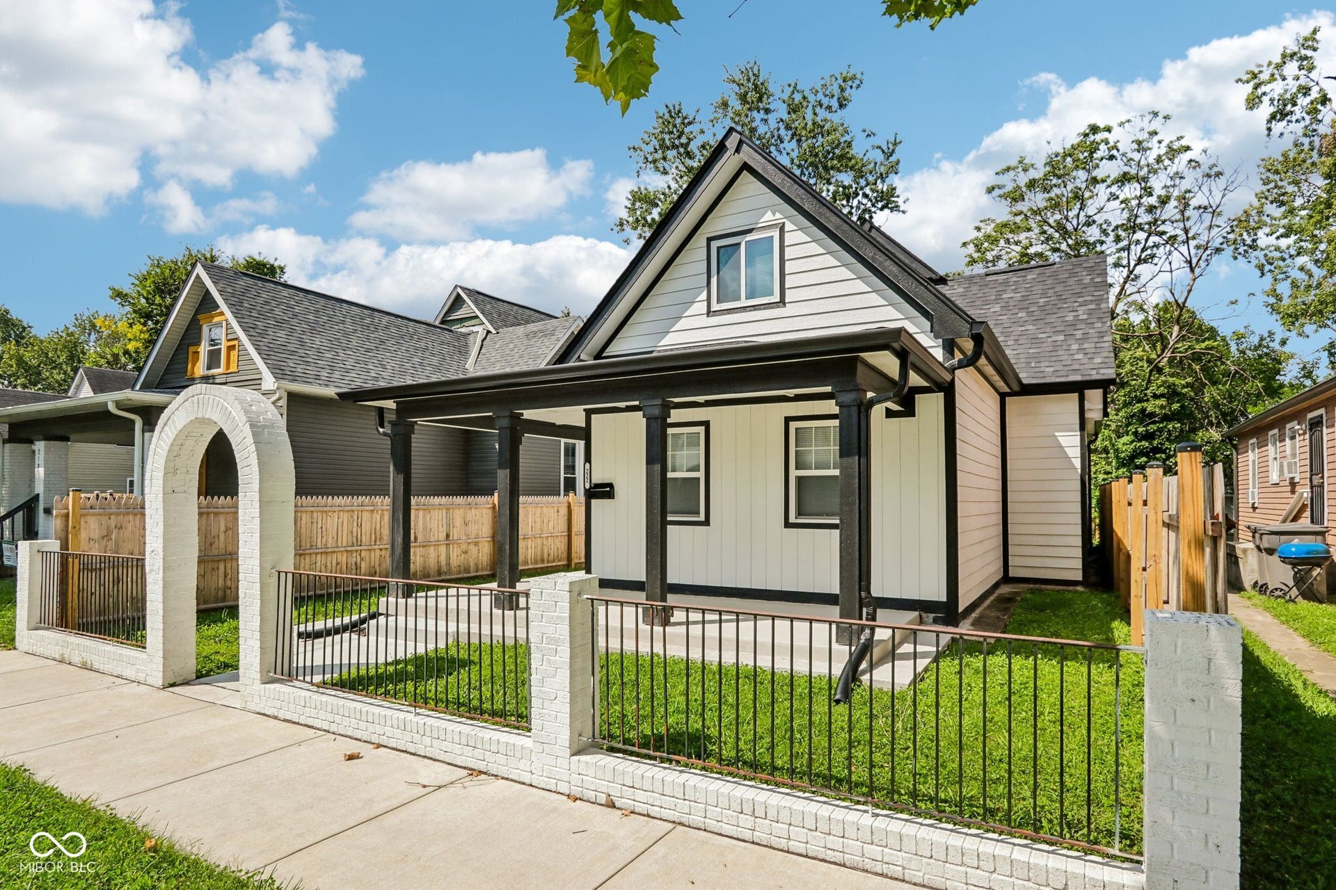 White siding exterior with black trim, a covered front porch, and a gabled roof
