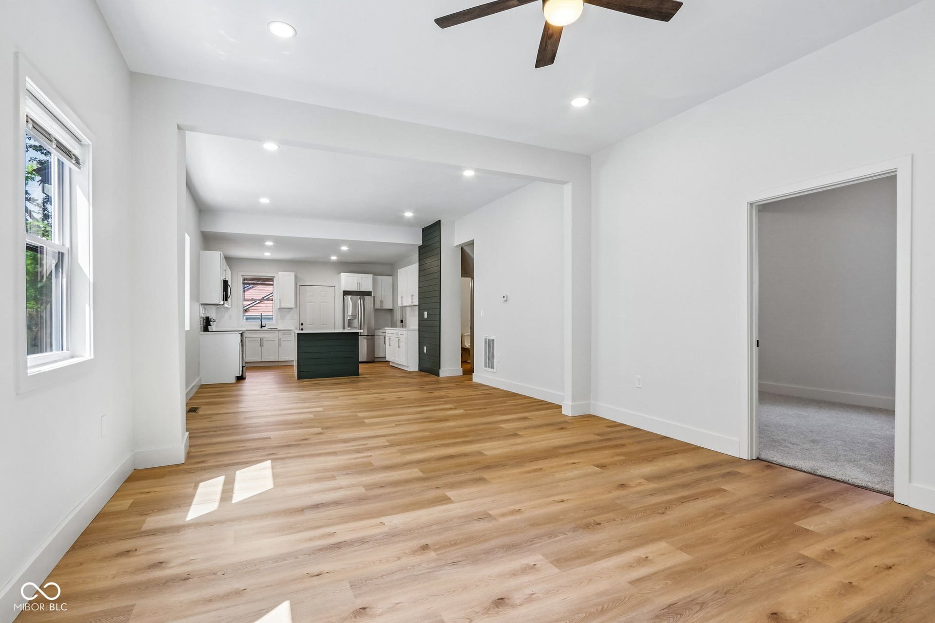 Recessed lighting, wood-finish flooring, ceiling fan, white cabinetry, and a dark accent wall