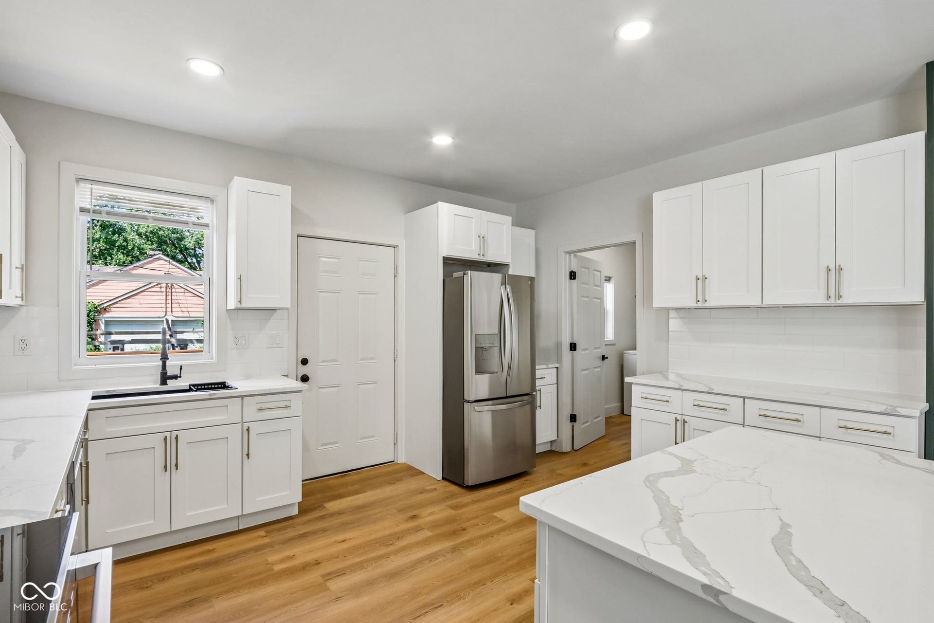 Kitchen featuring wood-finish flooring, white cabinetry, stainless steel appliances, and solid surface countertops