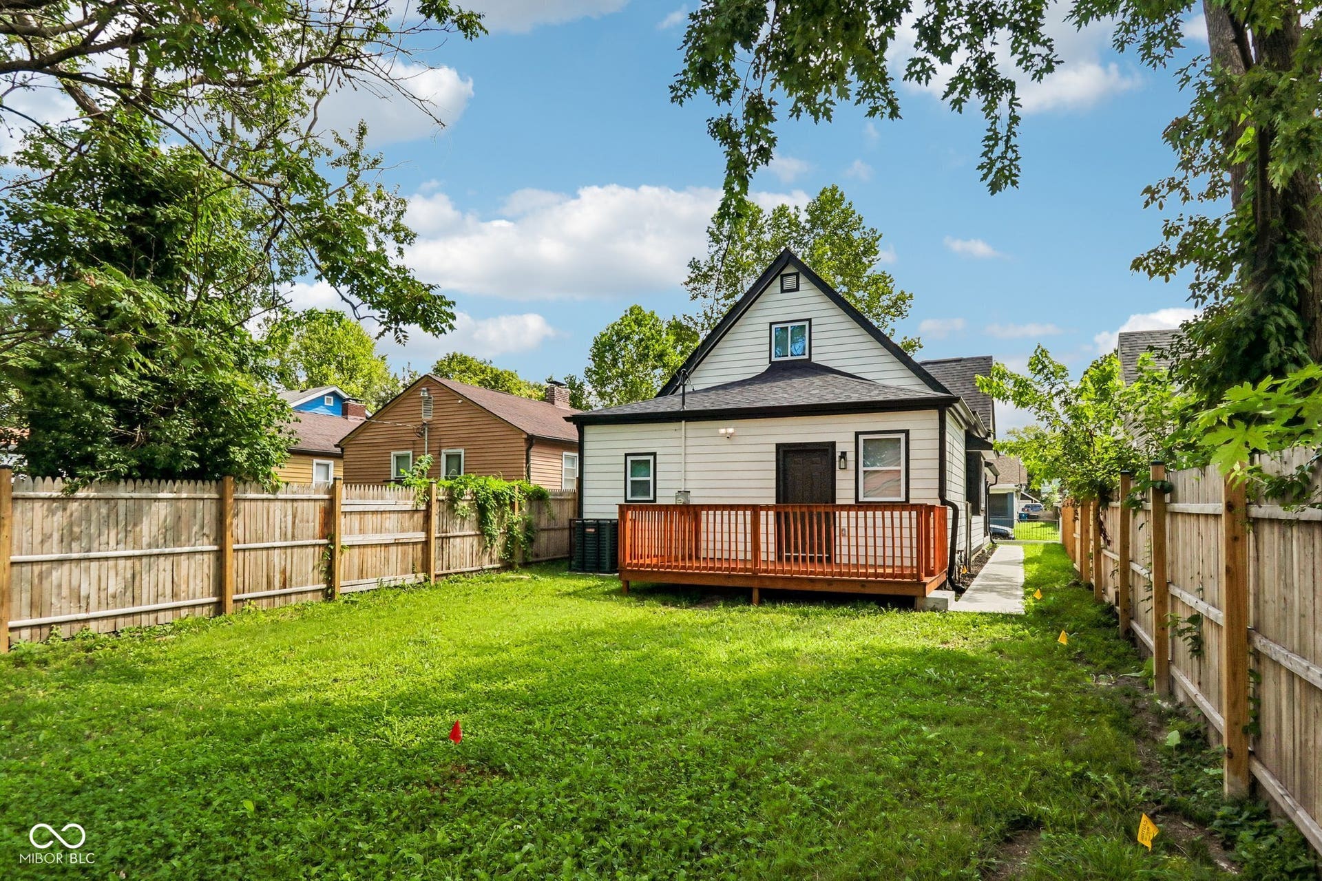 Expansive grass yard with wood fencing, a private wood deck, and white siding