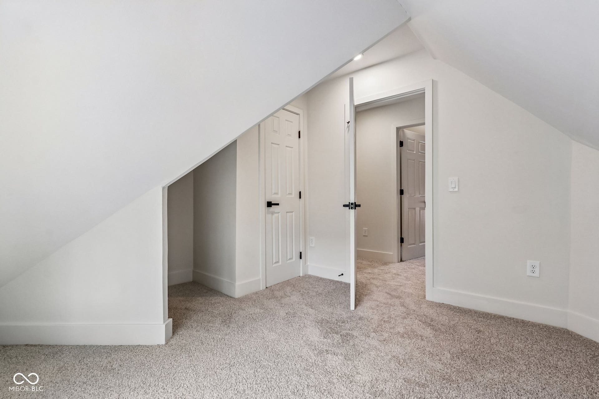Sloped ceilings, wall-to-wall carpeting, white doors with black hardware, and recessed lighting