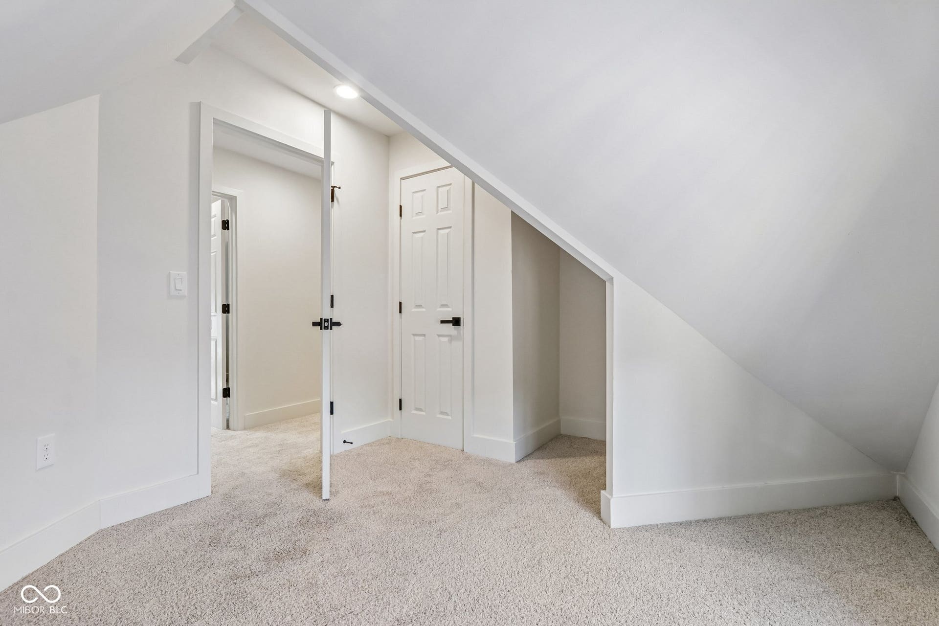 Carpeted room featuring an angled ceiling, recessed lighting, and a paneled door with black hardware