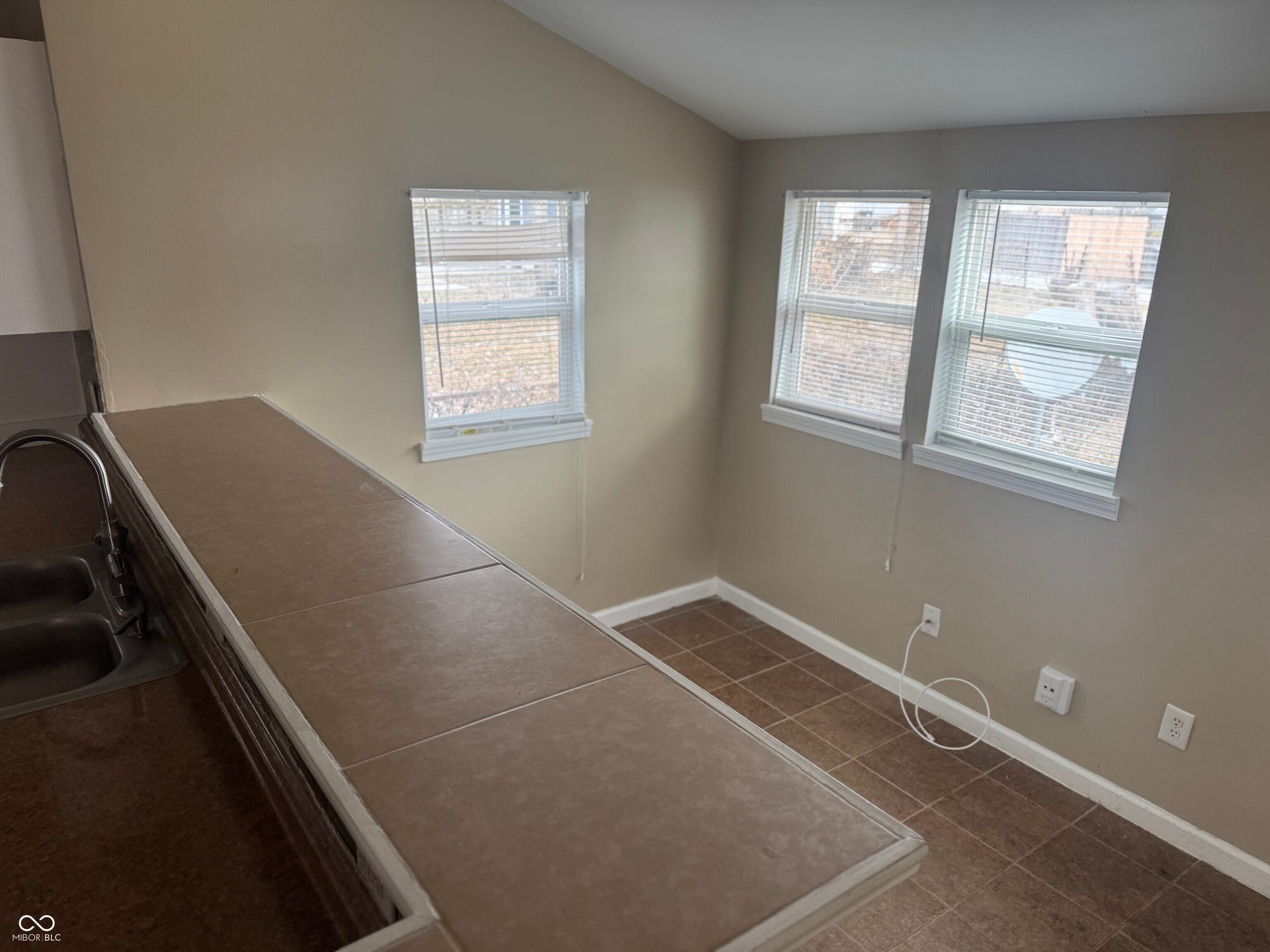 Virtually Altered - Tile flooring, multiple windows with blinds, dual basin sink with chrome faucet, light neutral wall paint