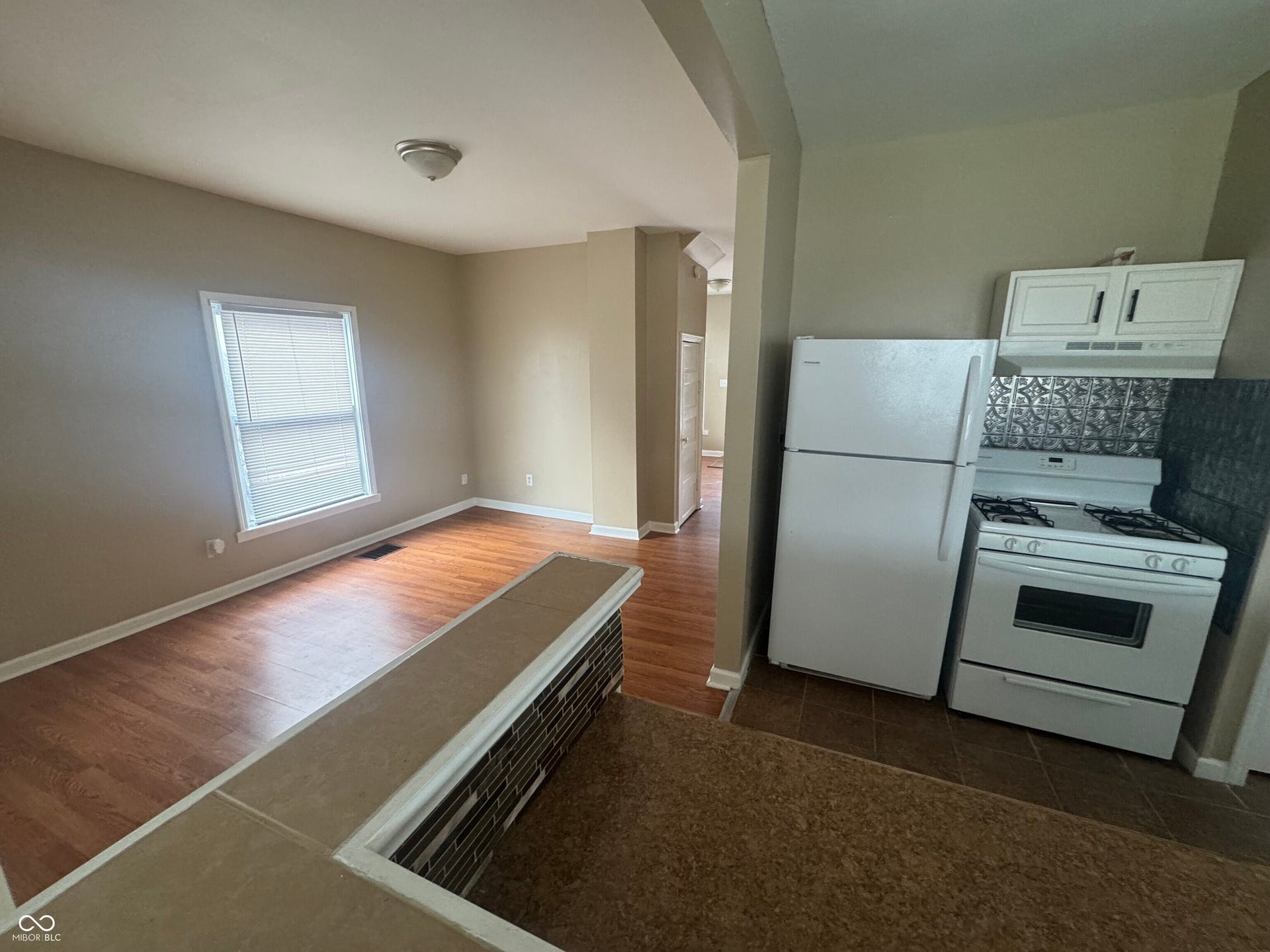 Virtually Altered - Wood-finish flooring, white window blinds, white kitchen cabinetry, white refrigerator, and white range