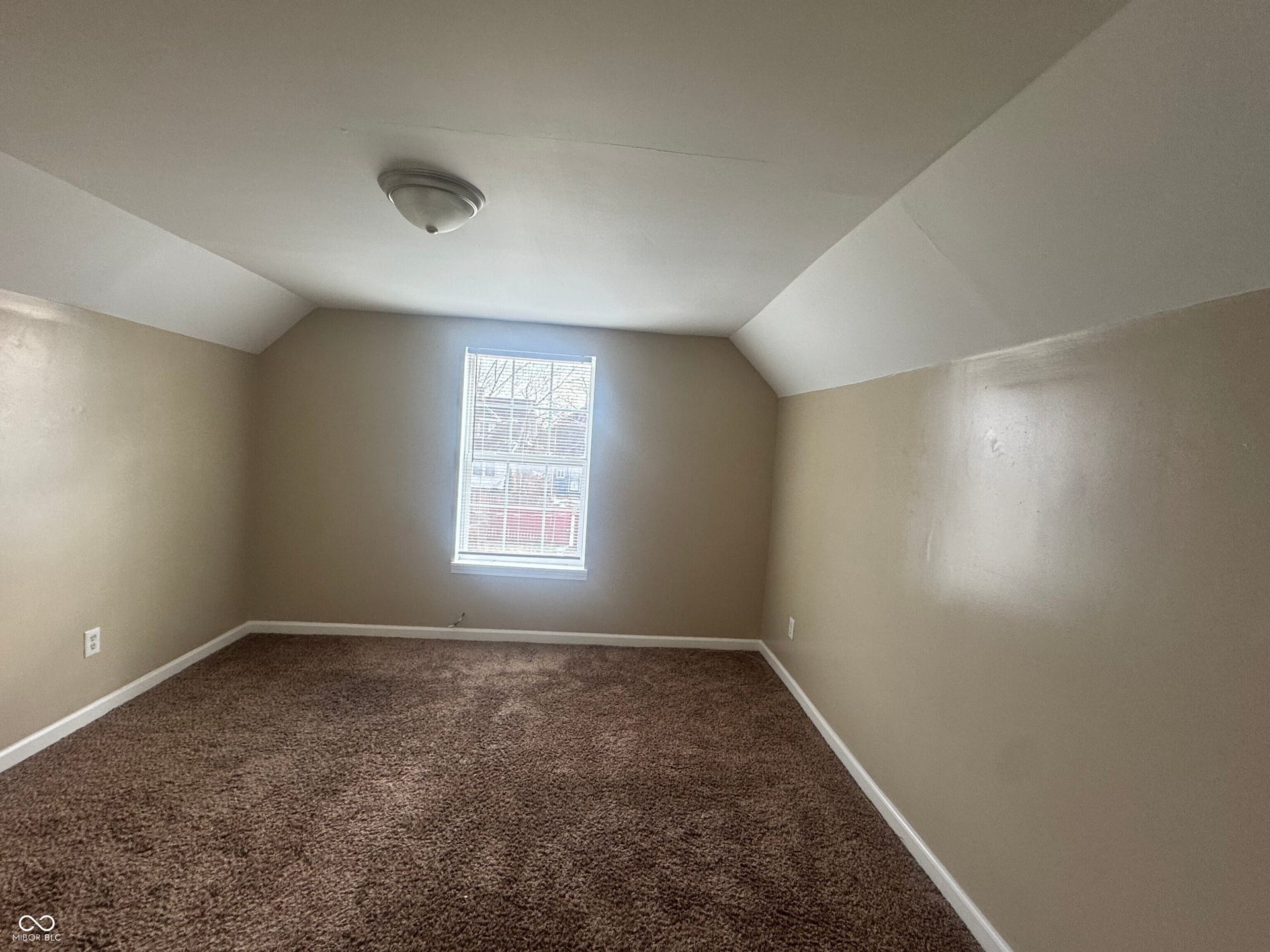 Virtually Altered - Window with grid pattern, neutral-toned walls, vaulted ceiling with white trim, brown carpet flooring, and a flush-mount ceiling light fixture
