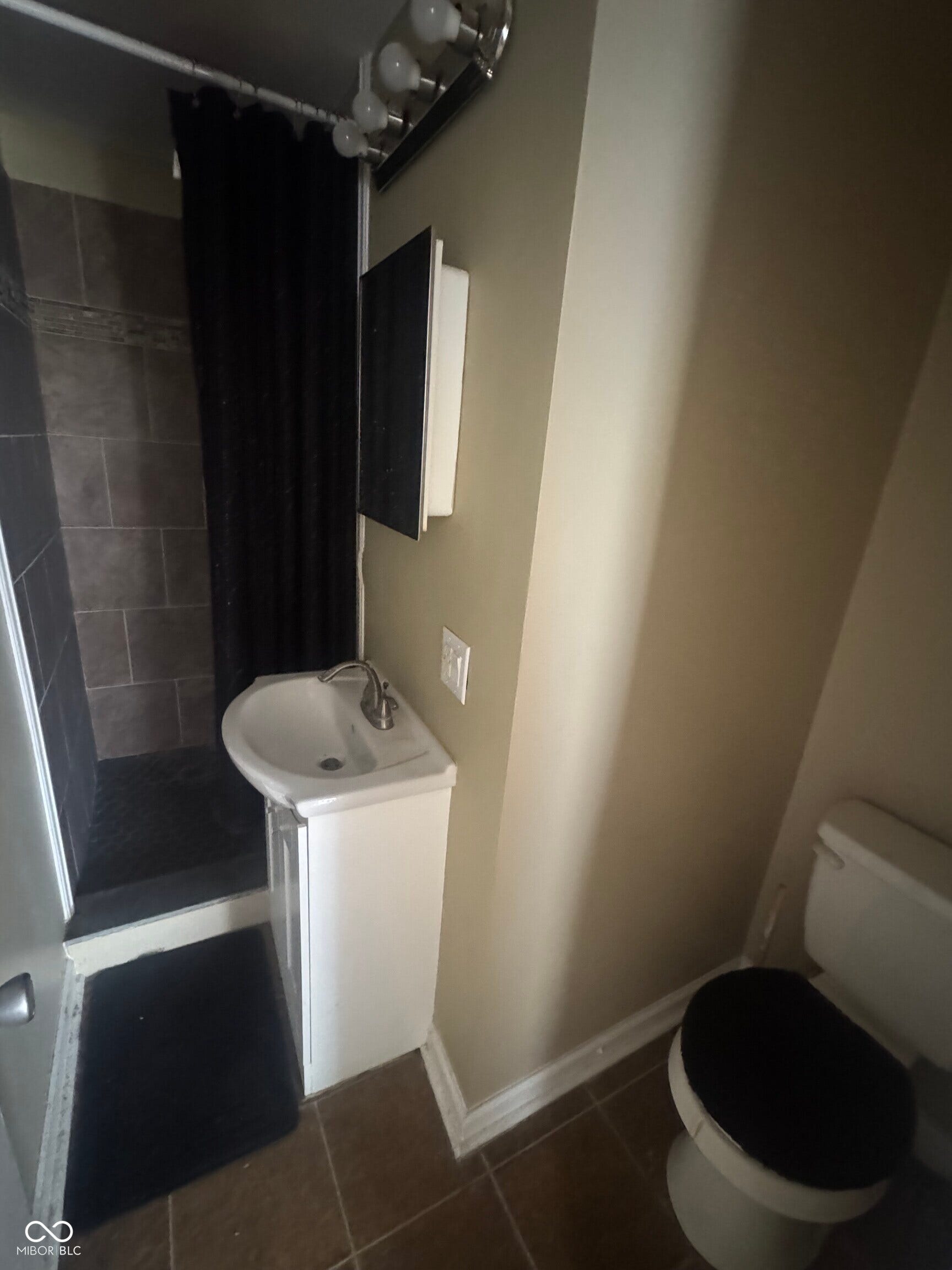 Virtually Altered - Tiled shower with dark grout, a wall-mounted medicine cabinet with a mirror, a compact sink vanity, and light-toned wall paint
