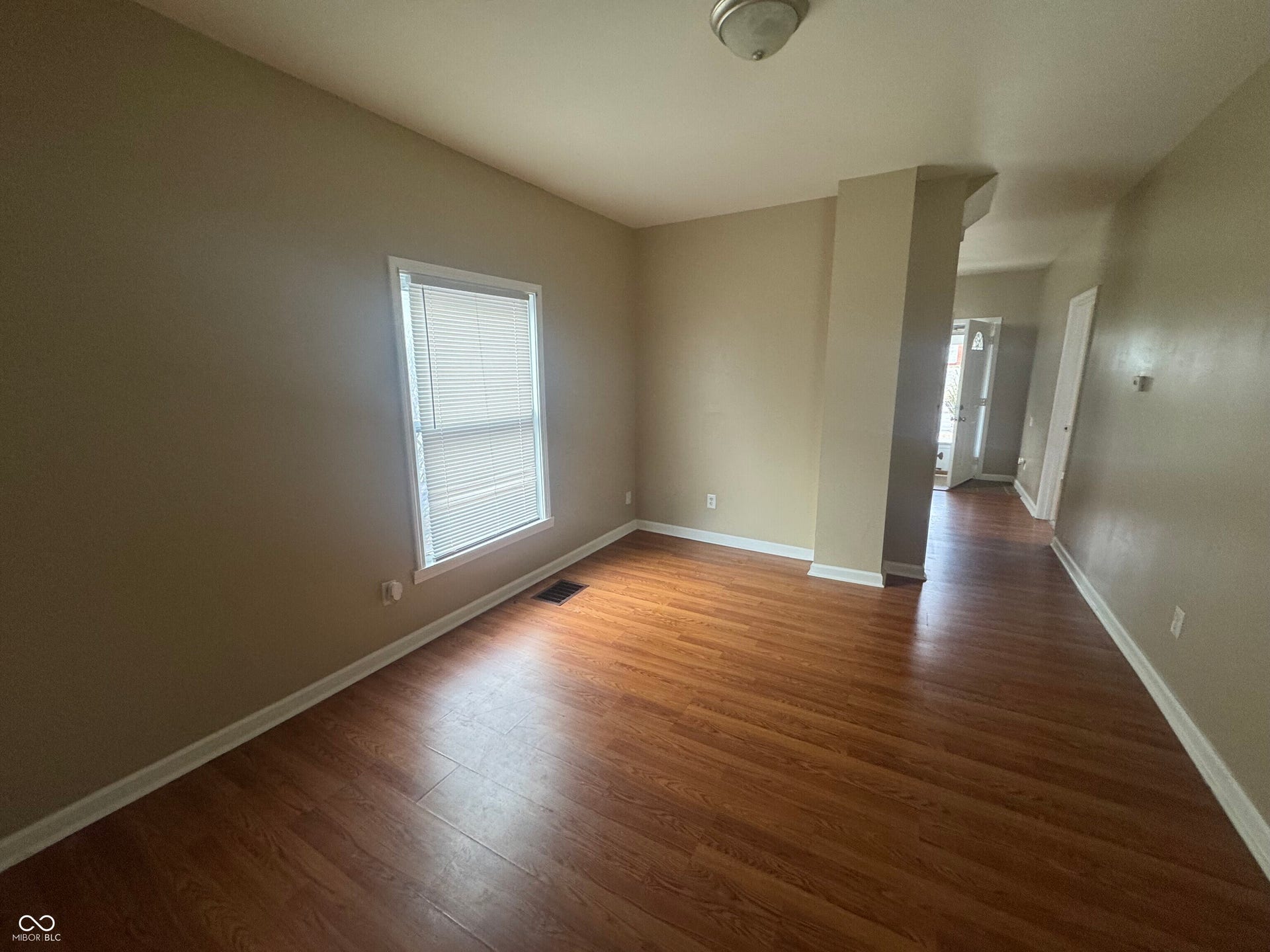 Virtually Altered - Wood-finish flooring, neutral wall tones, white trim, and a window with blinds