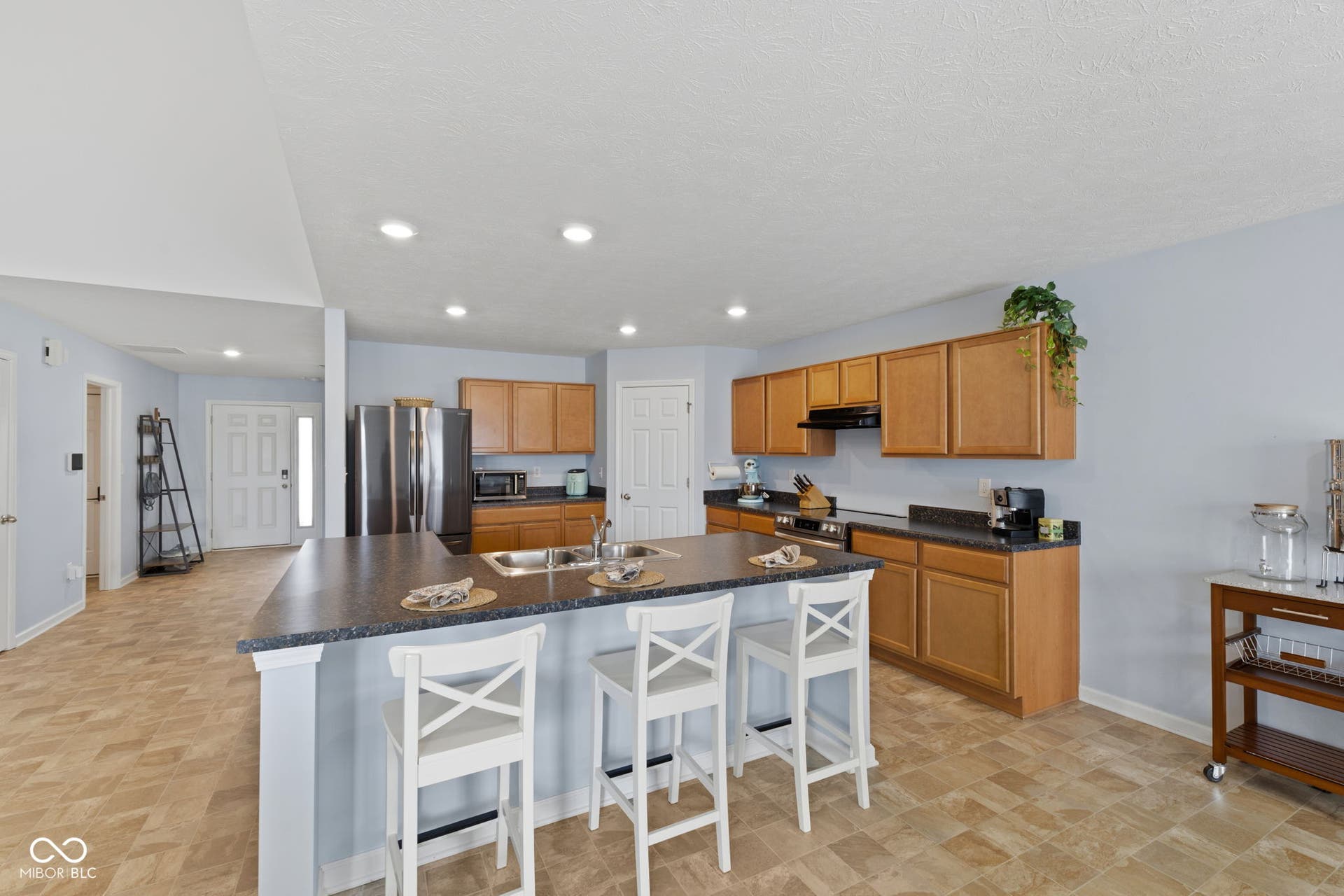4643 Darla Court, Indianapolis, IN 46239 Kitchen featuring wood-finish cabinetry, dark countertops, a double basin sink, and stainless steel appliances