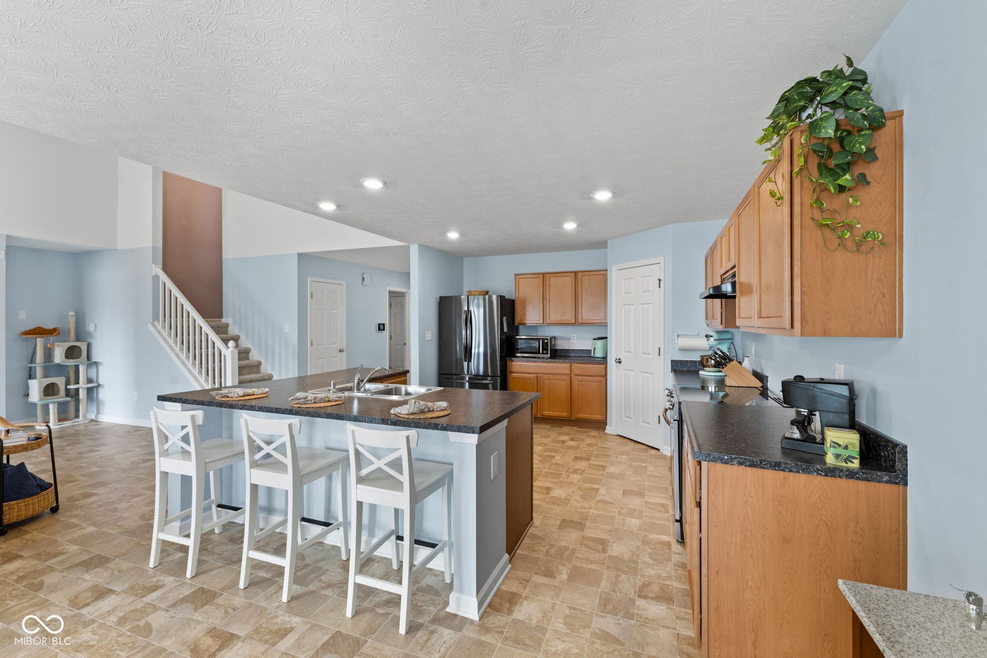 4643 Darla Court, Indianapolis, IN 46239 Kitchen featuring a large central island with seating, ample cabinetry, granite-look countertops, and stainless steel-finish appliances