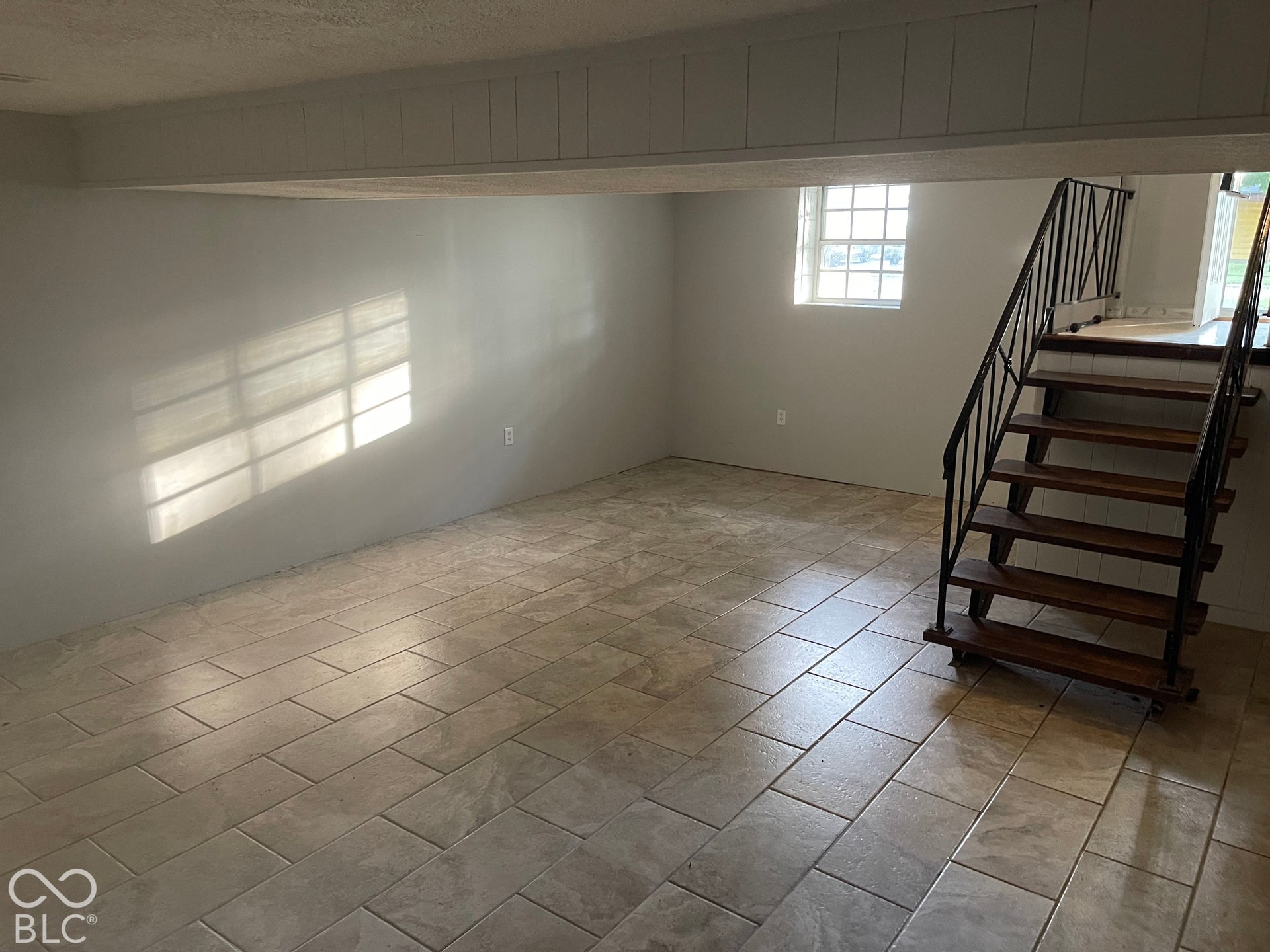 3913 Eisenhower Drive, Indianapolis, IN 46254 Tile flooring, white painted walls, exposed wood beam, wood stairs with metal railing, and a window with grid panes
