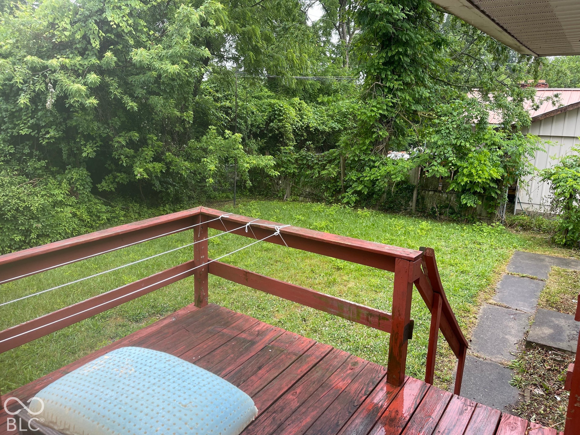 3913 Eisenhower Drive, Indianapolis, IN 46254 Wood-finish deck with a red railing and string balusters, overlooking a grassy yard with established trees
