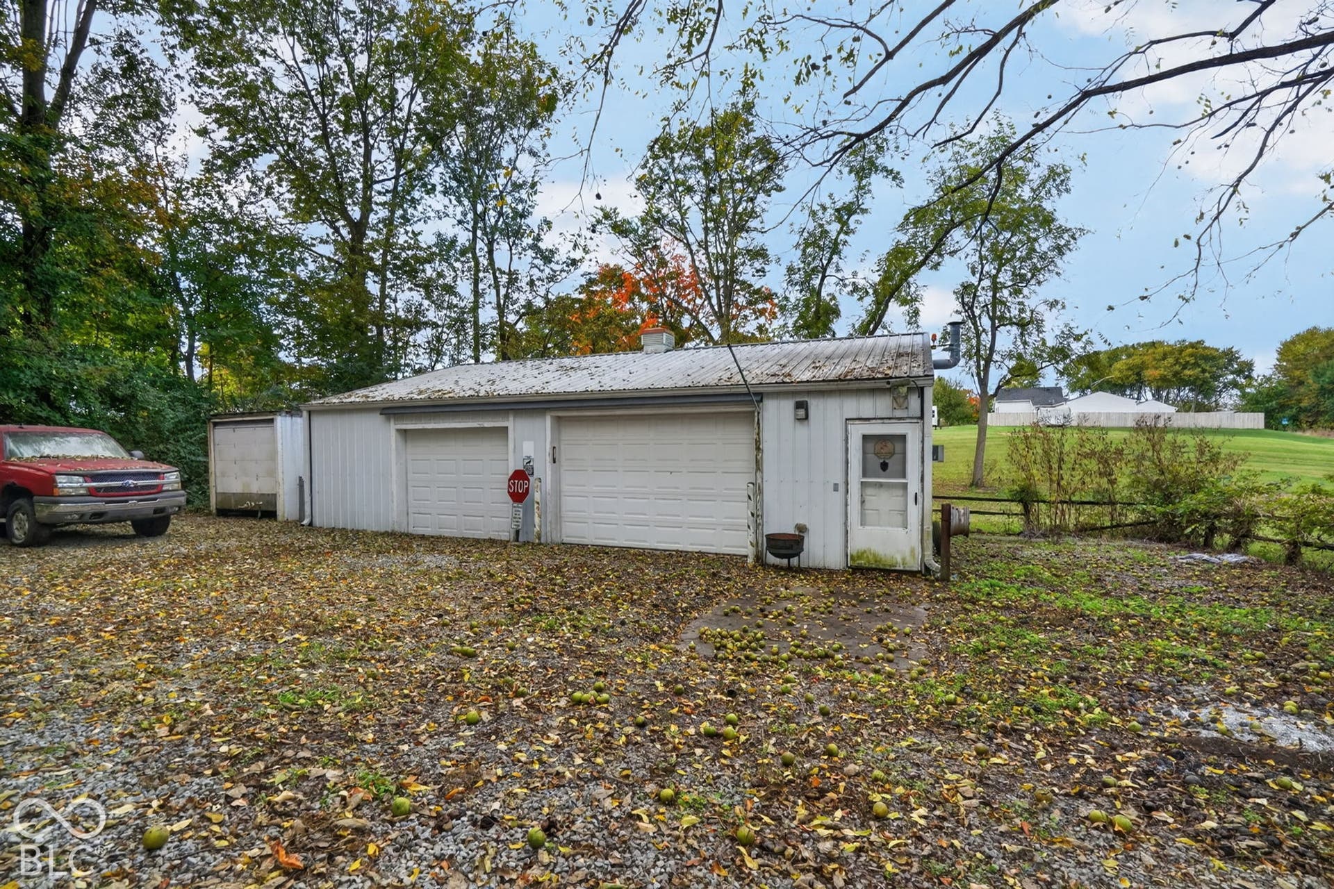 Detached garage featuring white vertical siding, two vehicle bays with sectional doors, a metal roof, and an exterior pass-through door