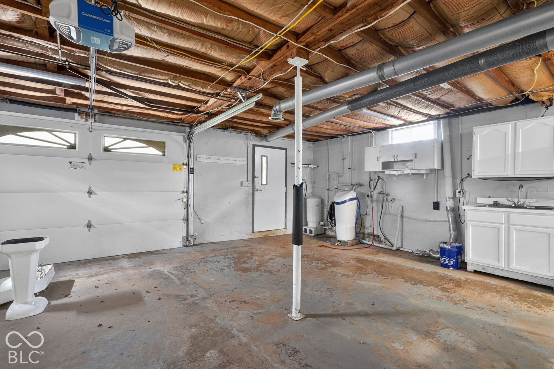 Garage featuring an automated overhead door with window inserts, built-in white cabinetry, integrated sink, and an exterior access door