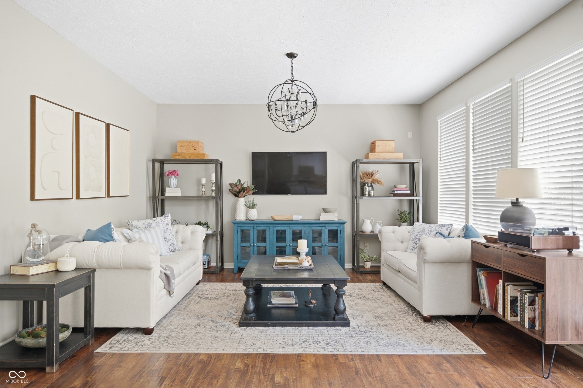 Bright living area featuring wood-finish flooring, neutral wall tones, and a decorative chandelier