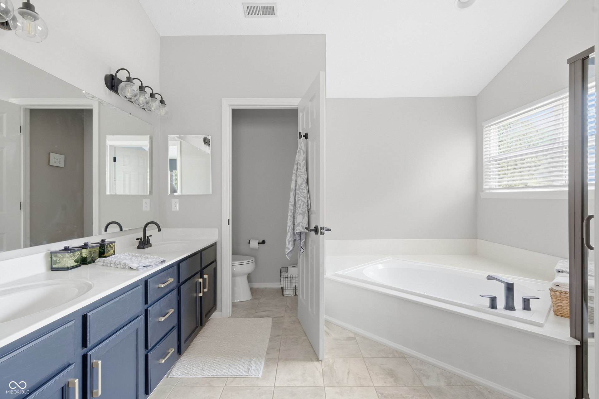 Dual vanity with blue cabinetry, white countertop, and dark-finish fixtures