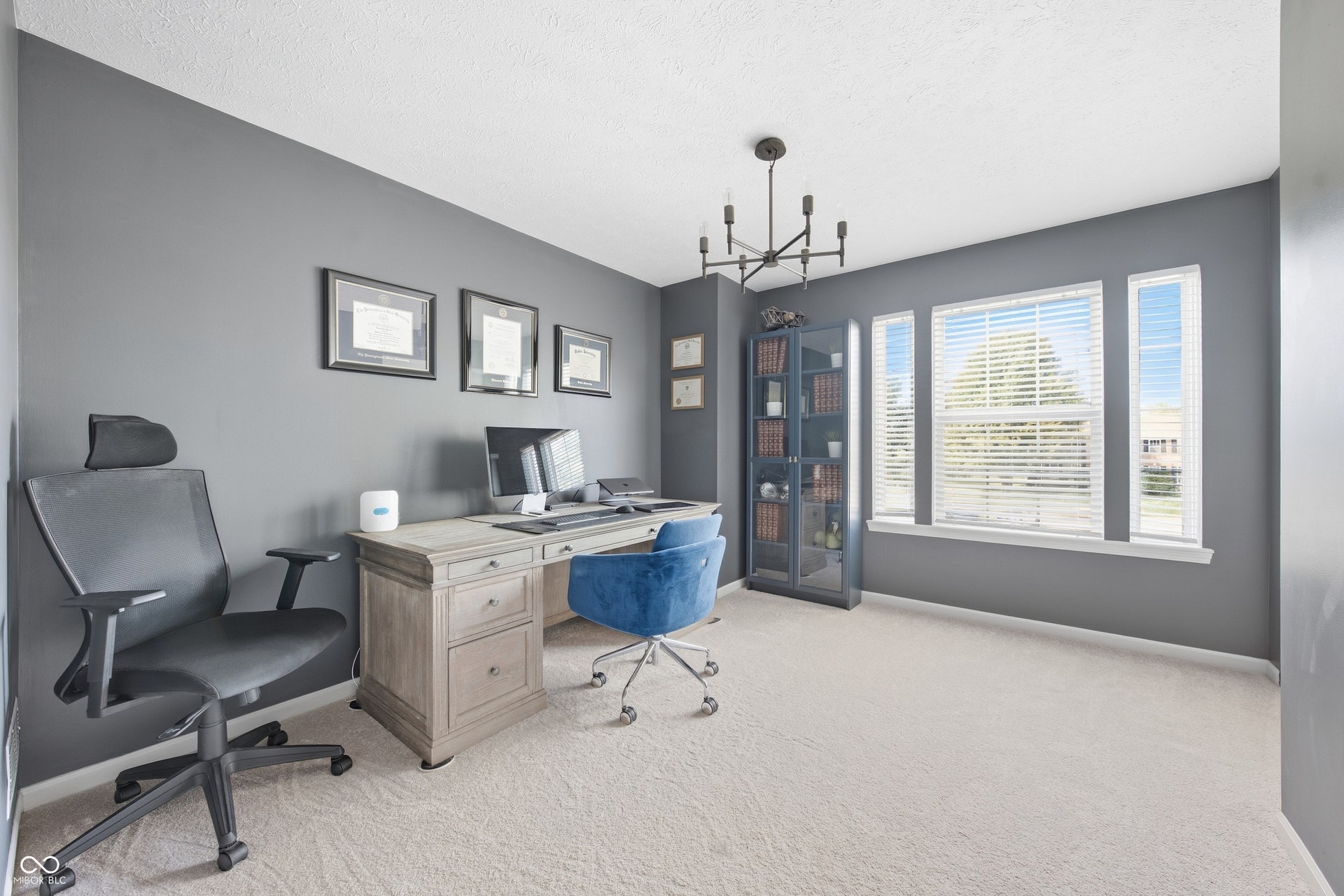 Neutral wall paint, carpet flooring, chandelier, multiple windows, built-in shelving