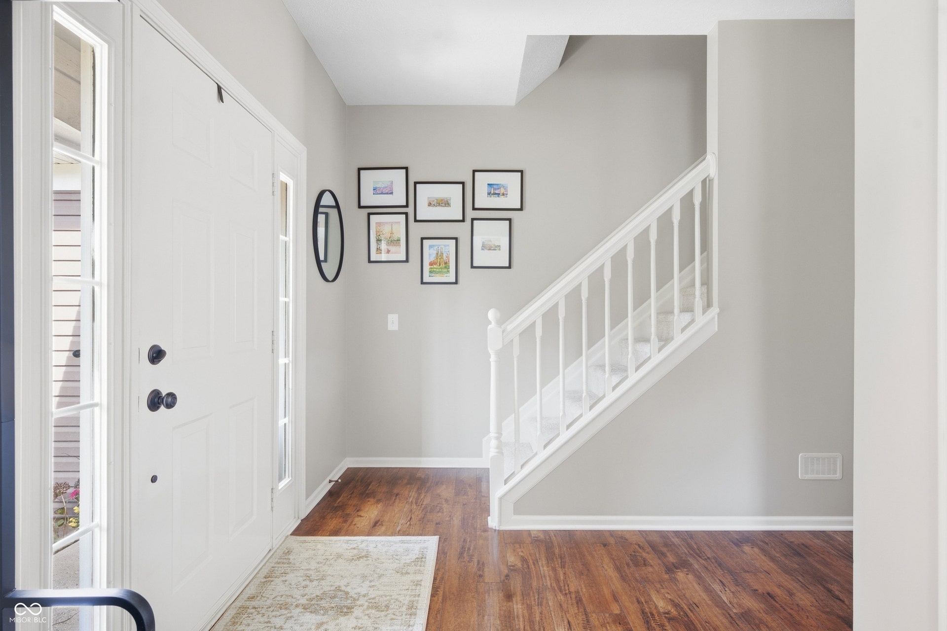 Entryway featuring a white paneled door with sidelights, dark finish hardware, and wood-finish flooring
