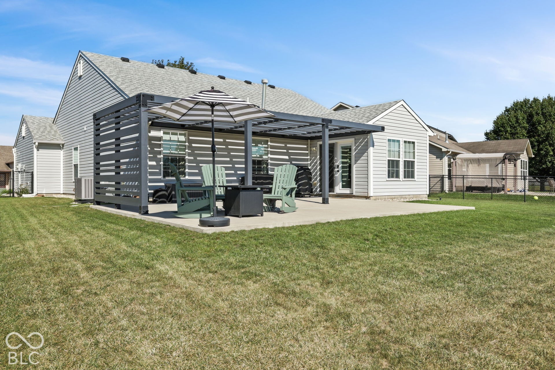 Rear exterior featuring a concrete patio, a metal-framed pergola with side privacy screening, and a fenced backyard