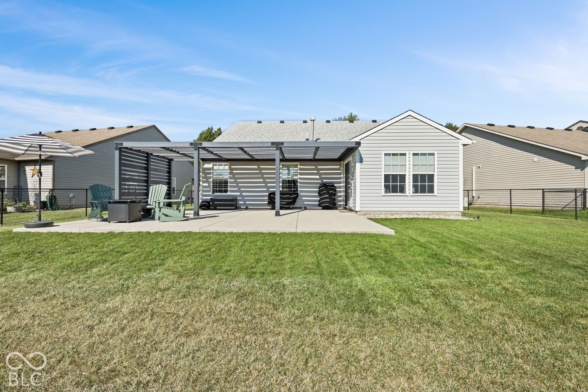Rear yard featuring a concrete patio, a metal-frame pergola with privacy screening, horizontal siding, and a fenced perimeter