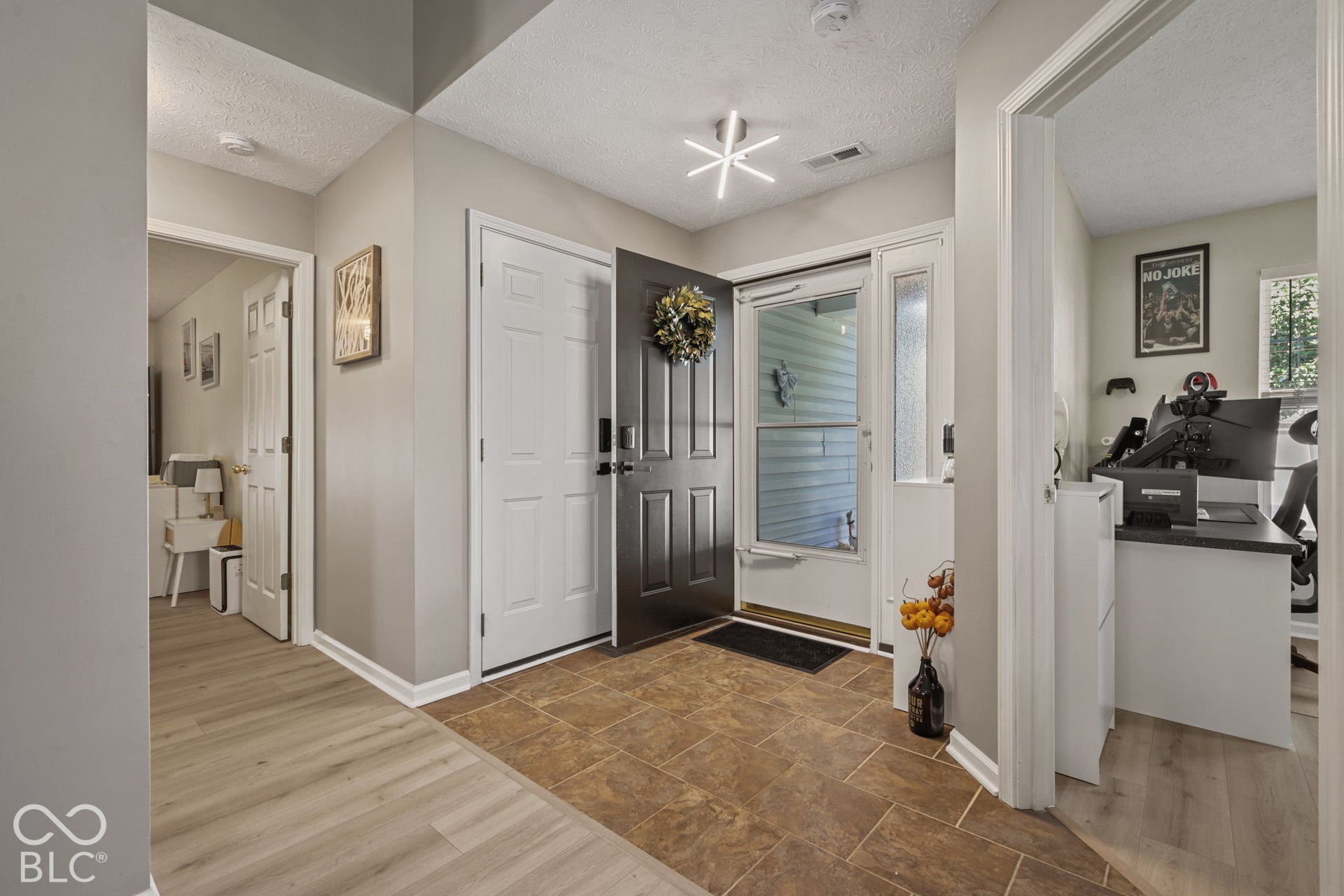 Entryway featuring tile flooring, wood-finish flooring, a dark-toned front door, and a multi-arm geometric ceiling light fixture