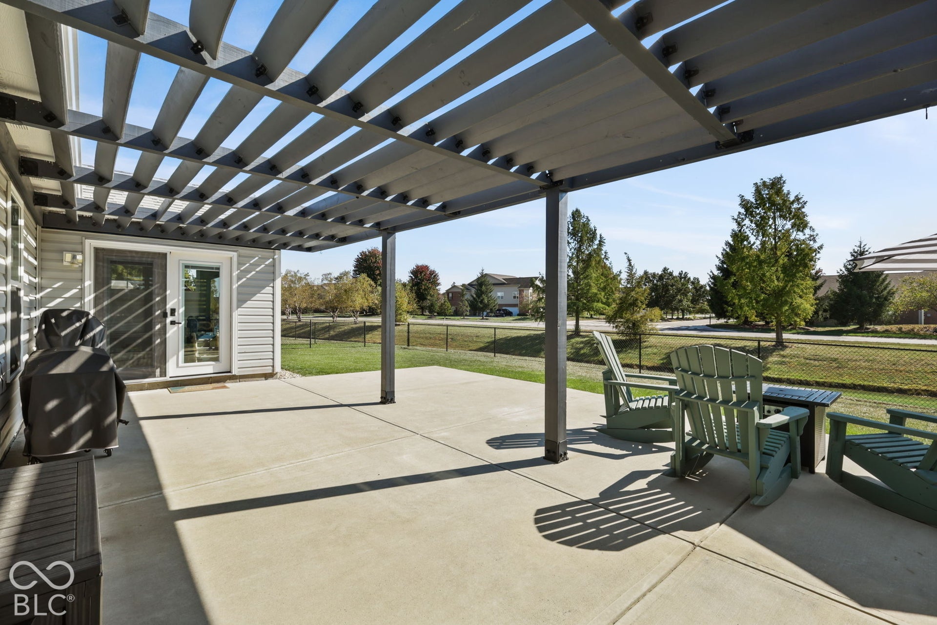Covered concrete patio featuring a metal pergola, siding exterior, and a chain-link fenced yard