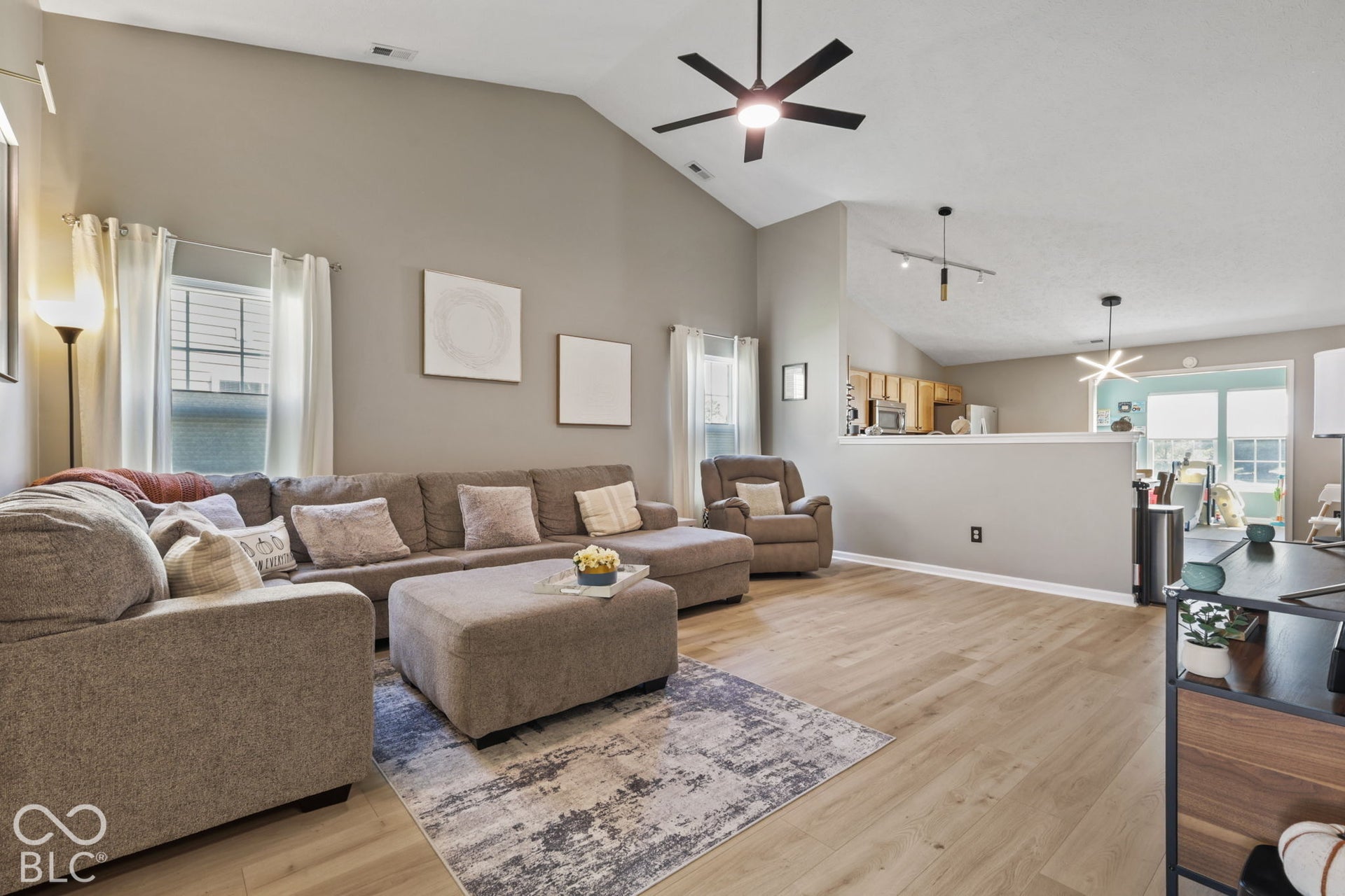 Vaulted ceilings, wood-finish flooring, matte black ceiling fan, and contemporary track lighting
