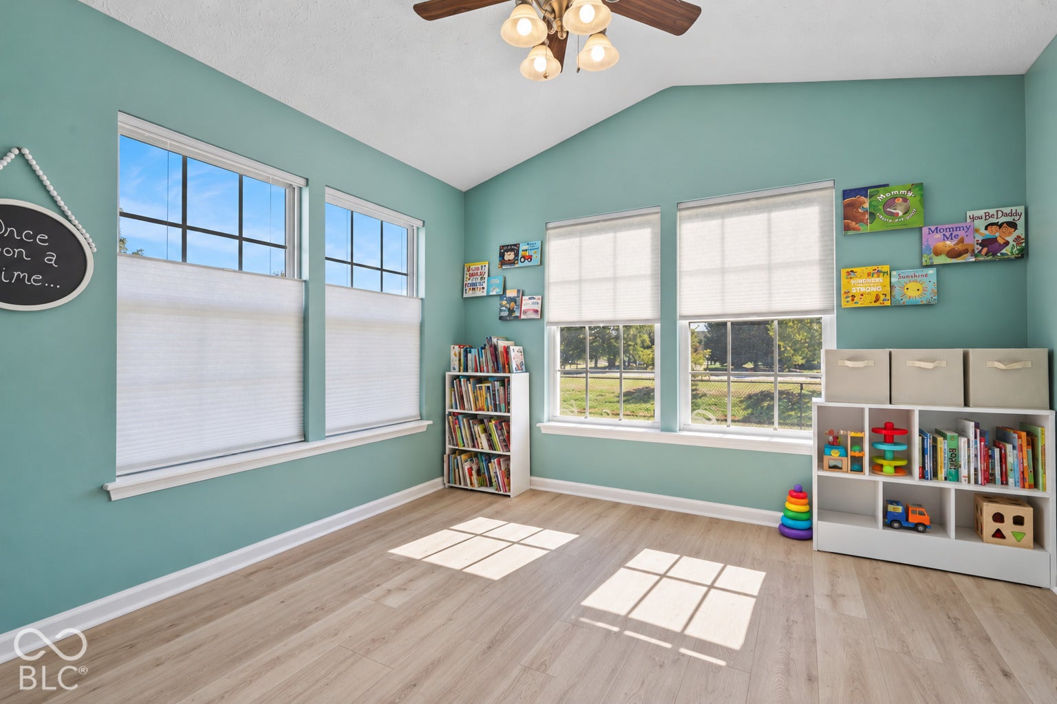 Vaulted ceiling featuring a central multi-light fixture, wood-finish flooring, and expansive windows