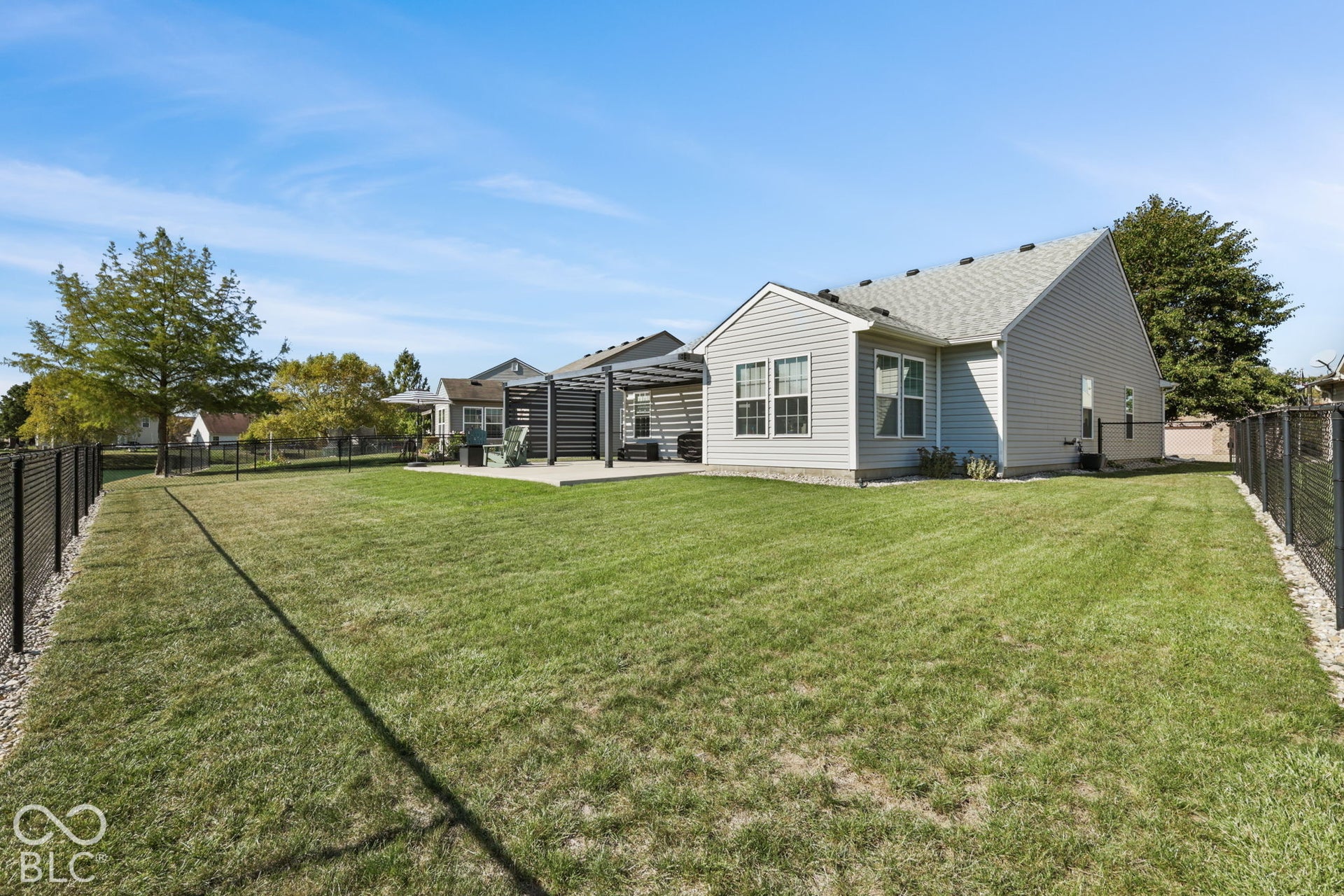 Fenced backyard featuring a concrete patio, a metal pergola, and siding exterior