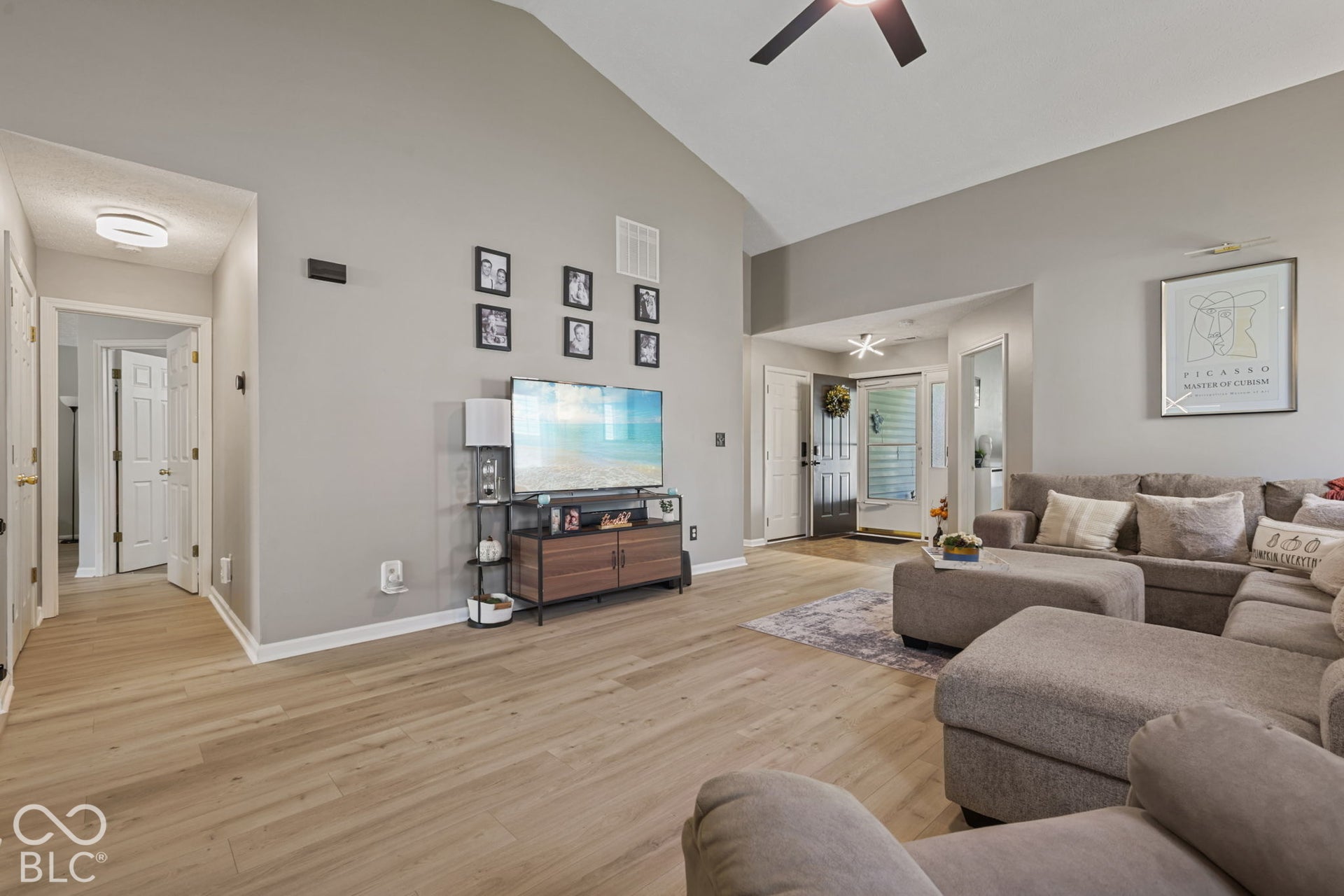 Vaulted ceiling with a central paddle fan, wood-finish flooring, and crisp neutral wall paint