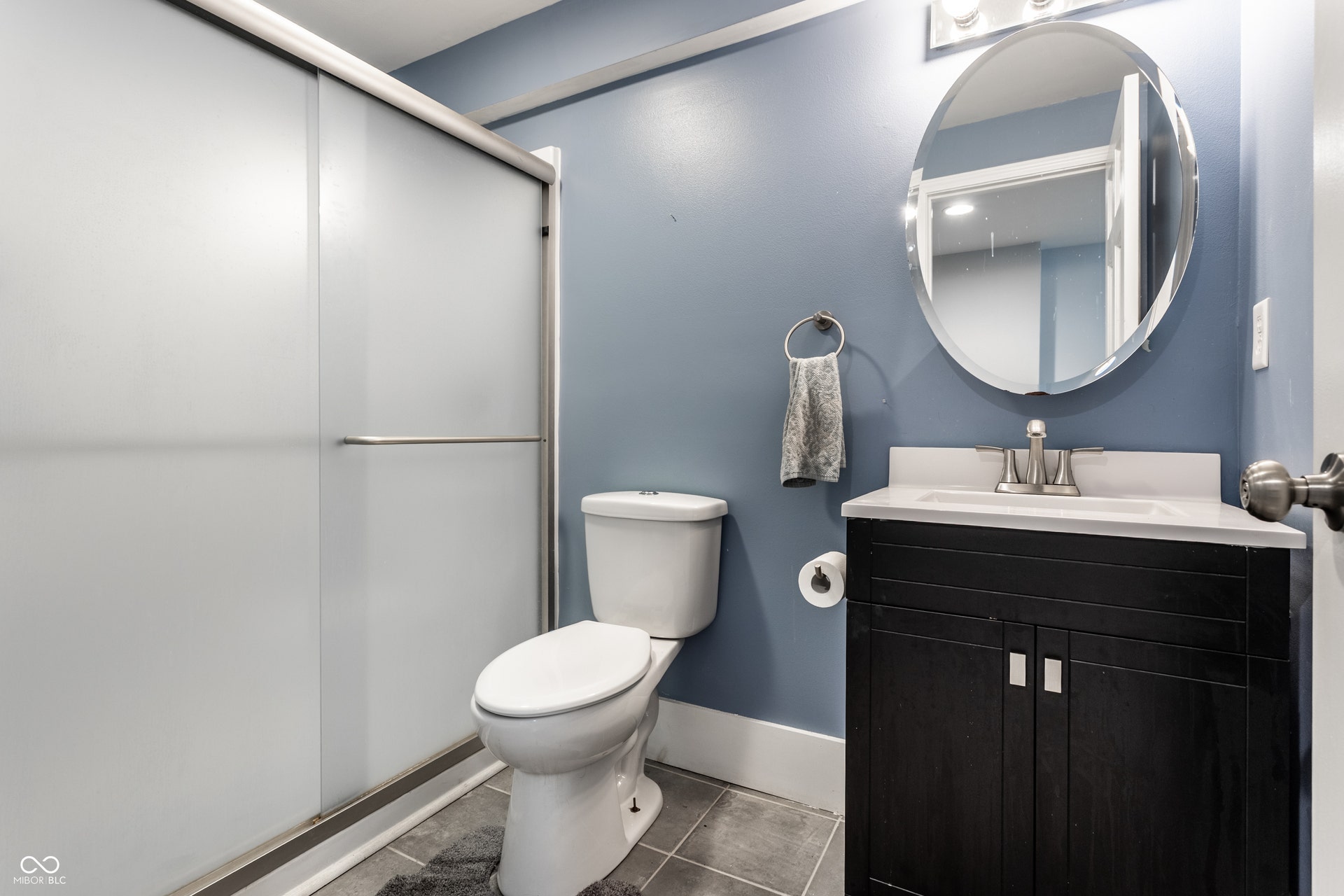 Frosted glass shower enclosure, dark wood-finish vanity with white countertop