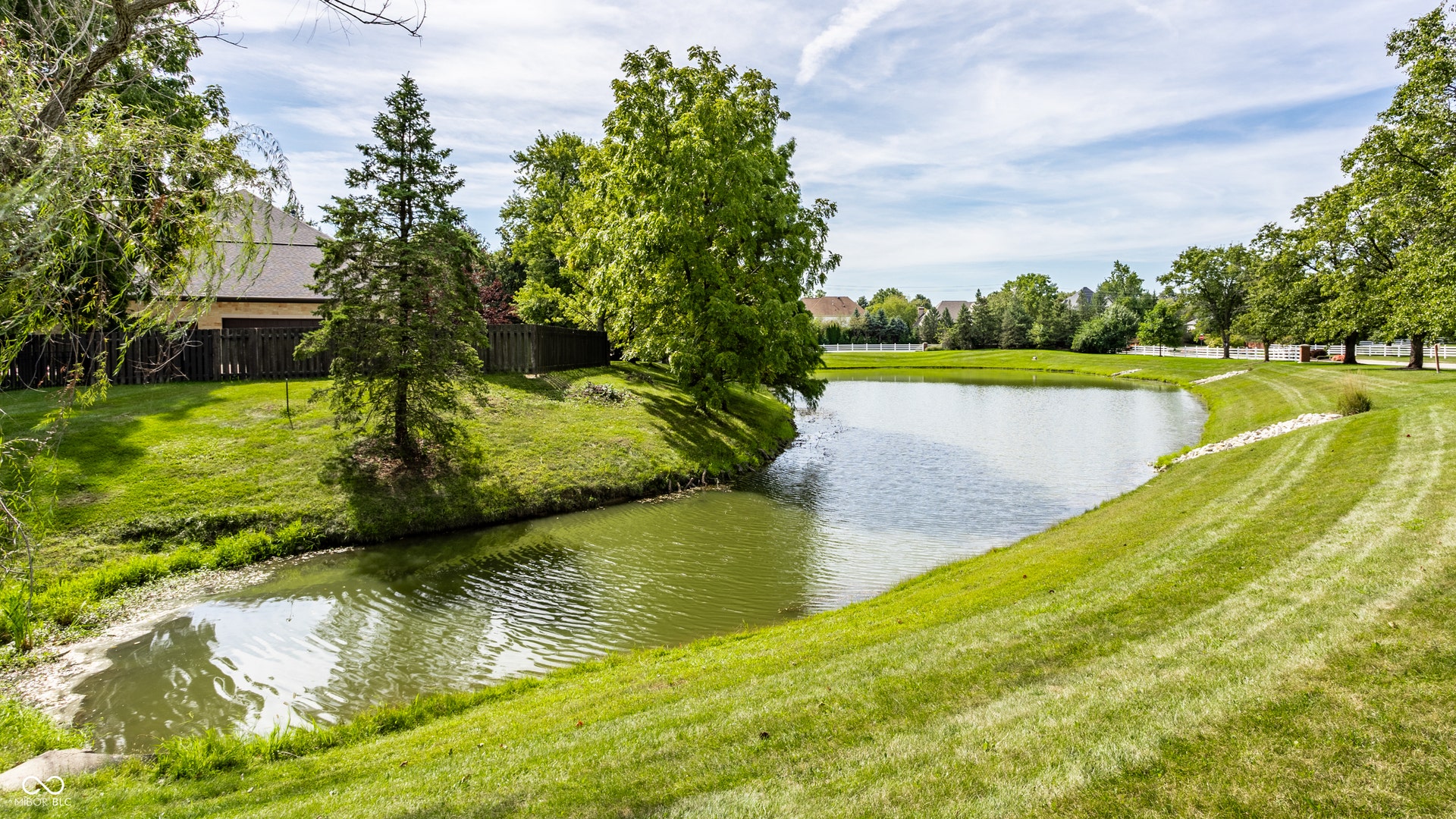 Expansive green space featuring a large pond and mature trees