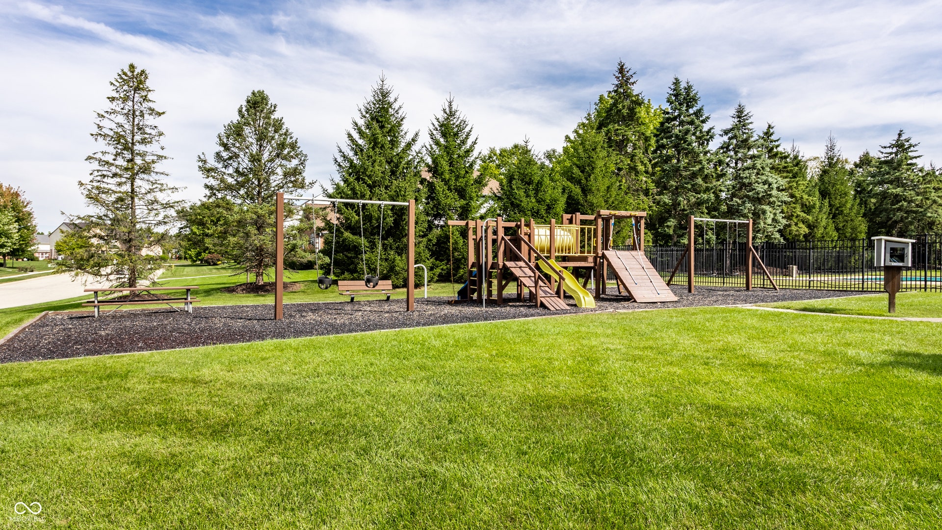 Expansive lawn area featuring a playground with swings, slides, and climbing structures