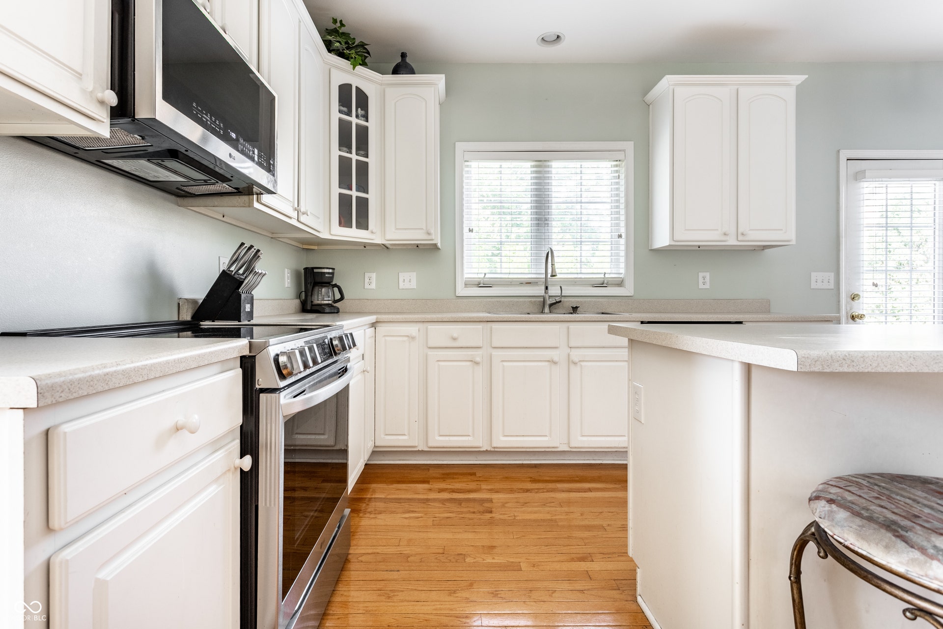 Kitchen featuring white cabinetry, light countertops, wood-finish flooring, stainless steel appliances, and a kitchen island