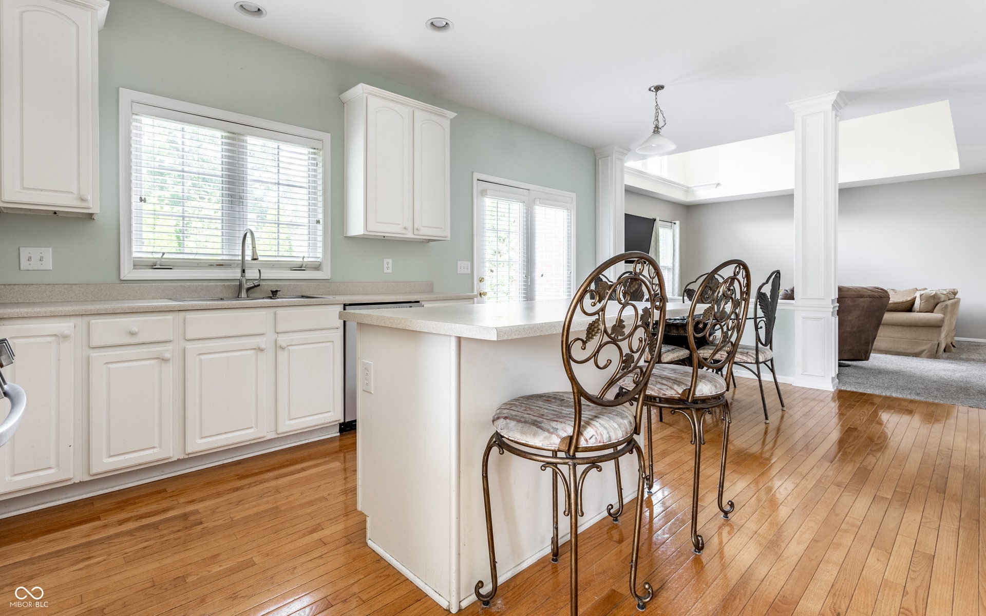 Kitchen featuring white cabinetry, light-toned countertops, a center island, wood-finish flooring, and recessed lighting