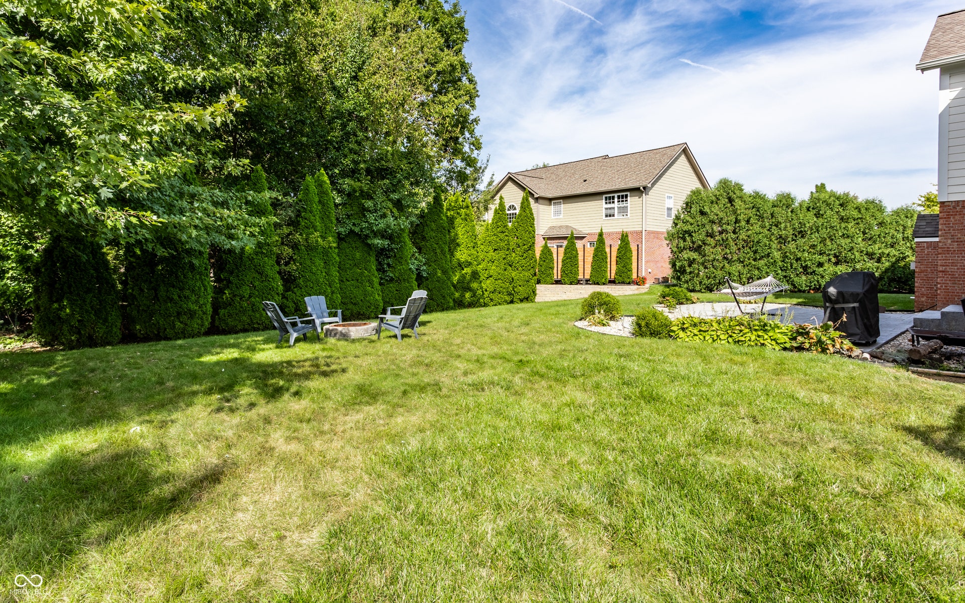 Spacious backyard with a large lawn, mature trees, and privacy landscaping