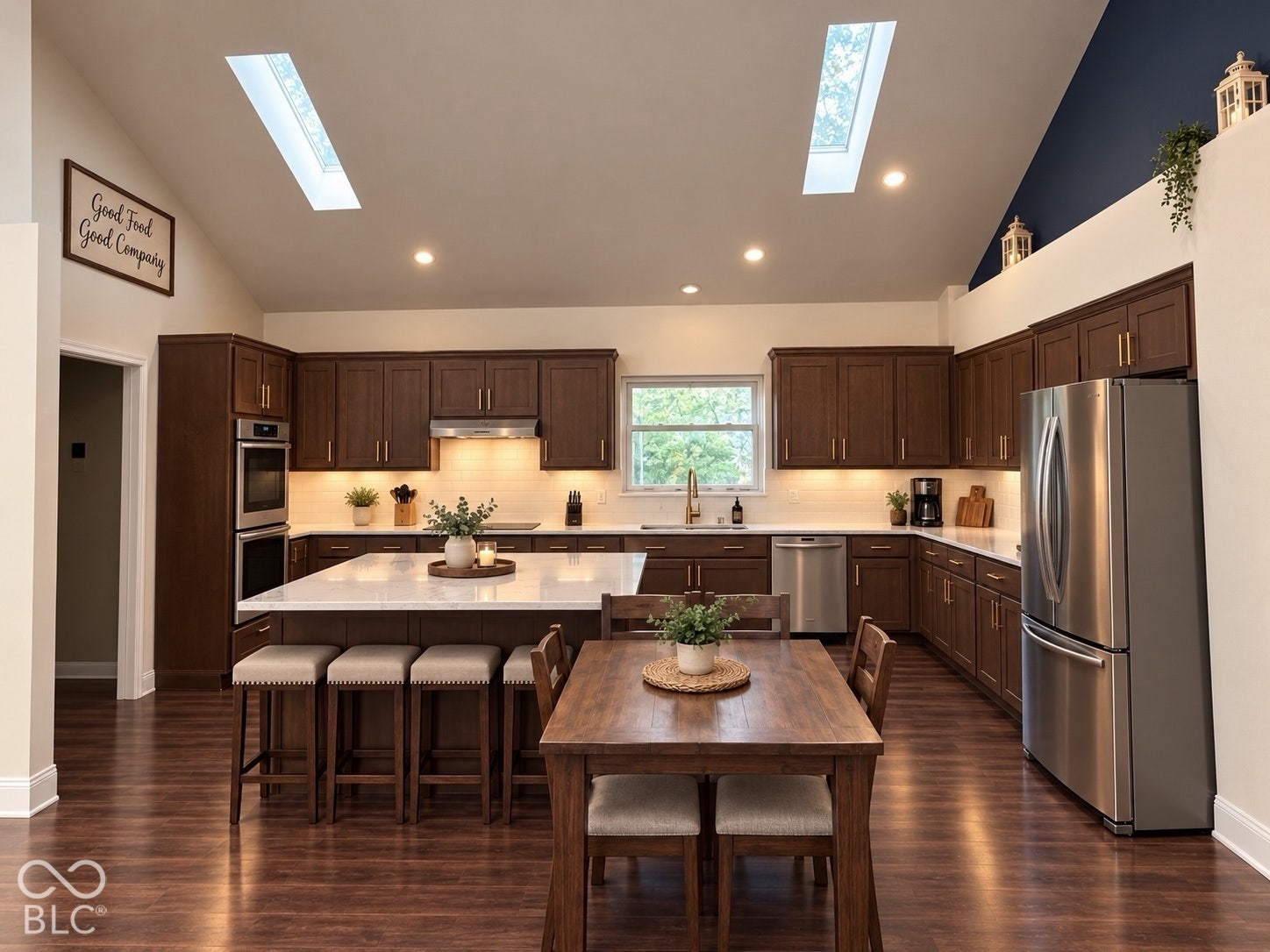 Virtually Altered - Kitchen featuring vaulted ceilings with dual skylights, dark wood-finish cabinetry, an expansive center island with quartz countertops, and stainless steel appliances