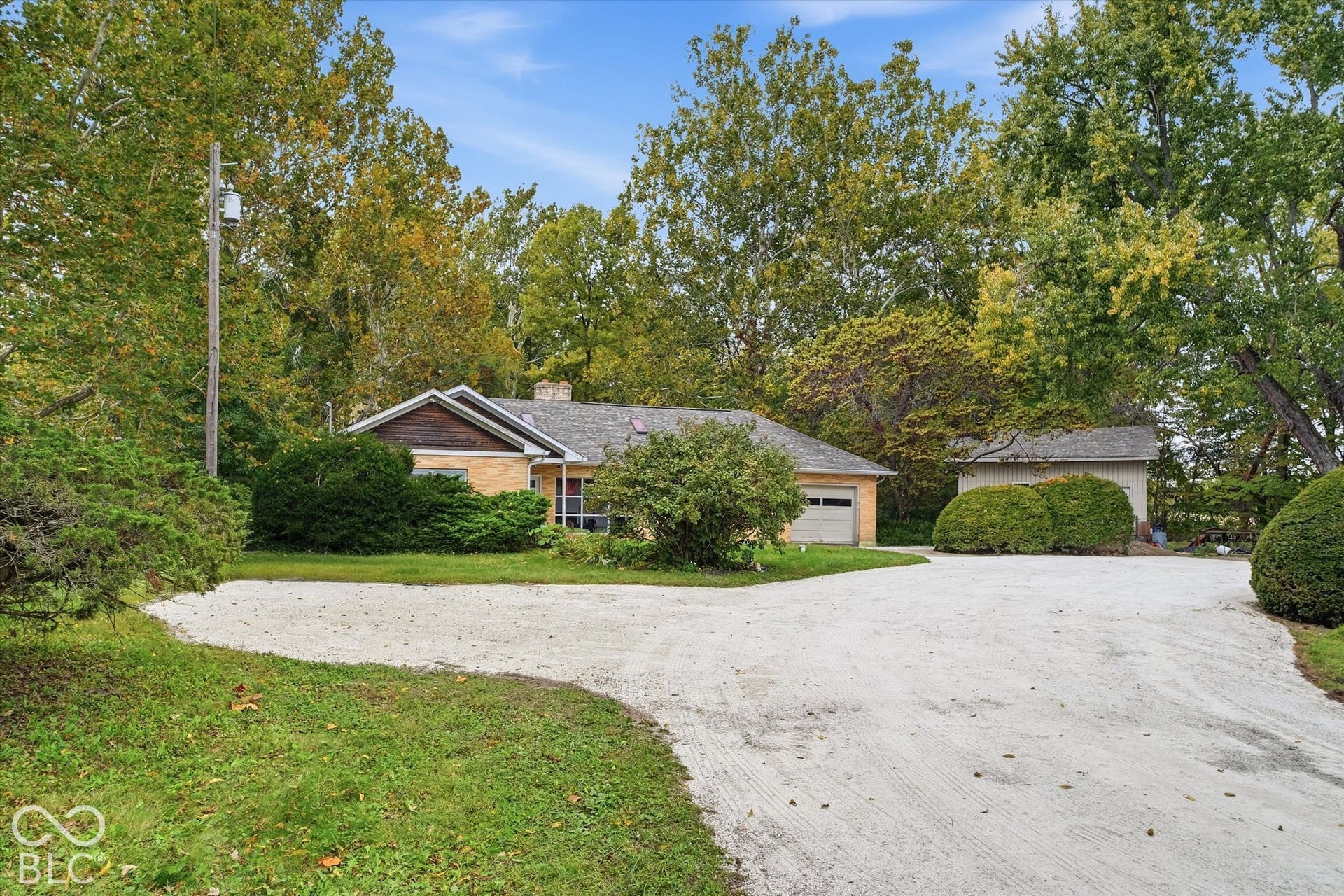Ranch-style residence featuring a brick and wood-paneled exterior, barn and an attached garage