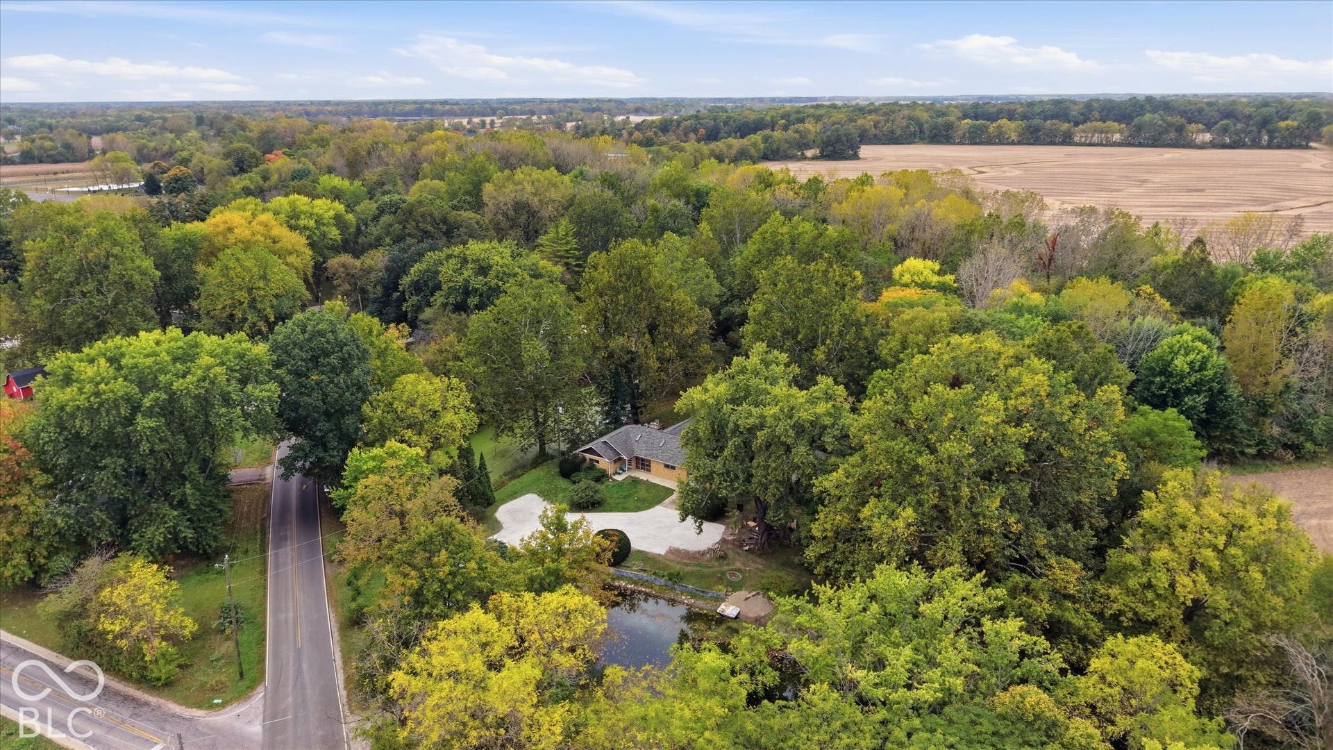 Mature trees surrounding the property, circular drive, private pond, and expansive natural landscaping