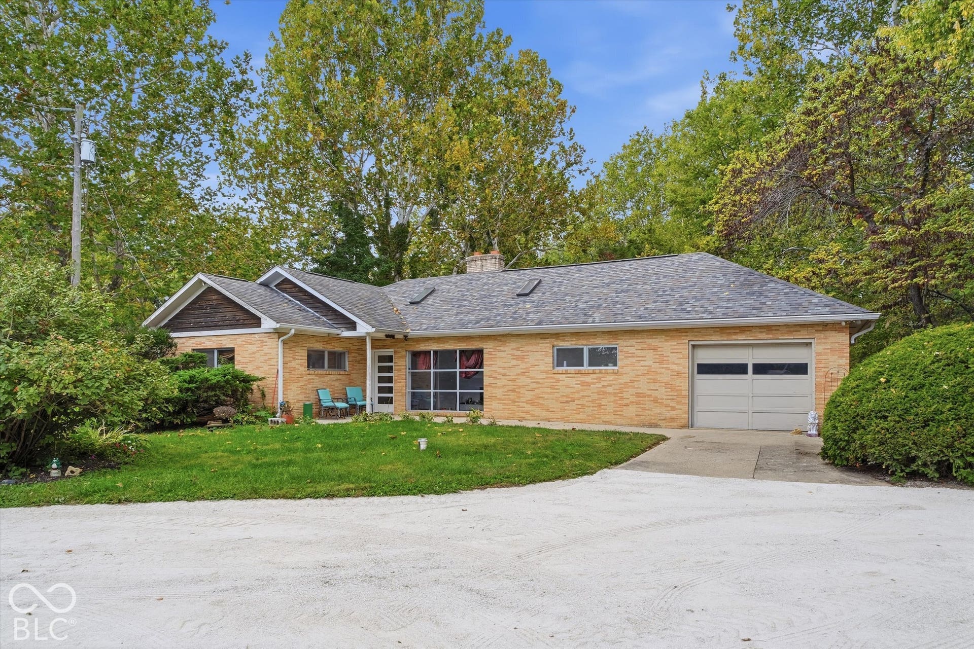 Brick exterior with a gabled roofline, attached garage, and mature landscaping