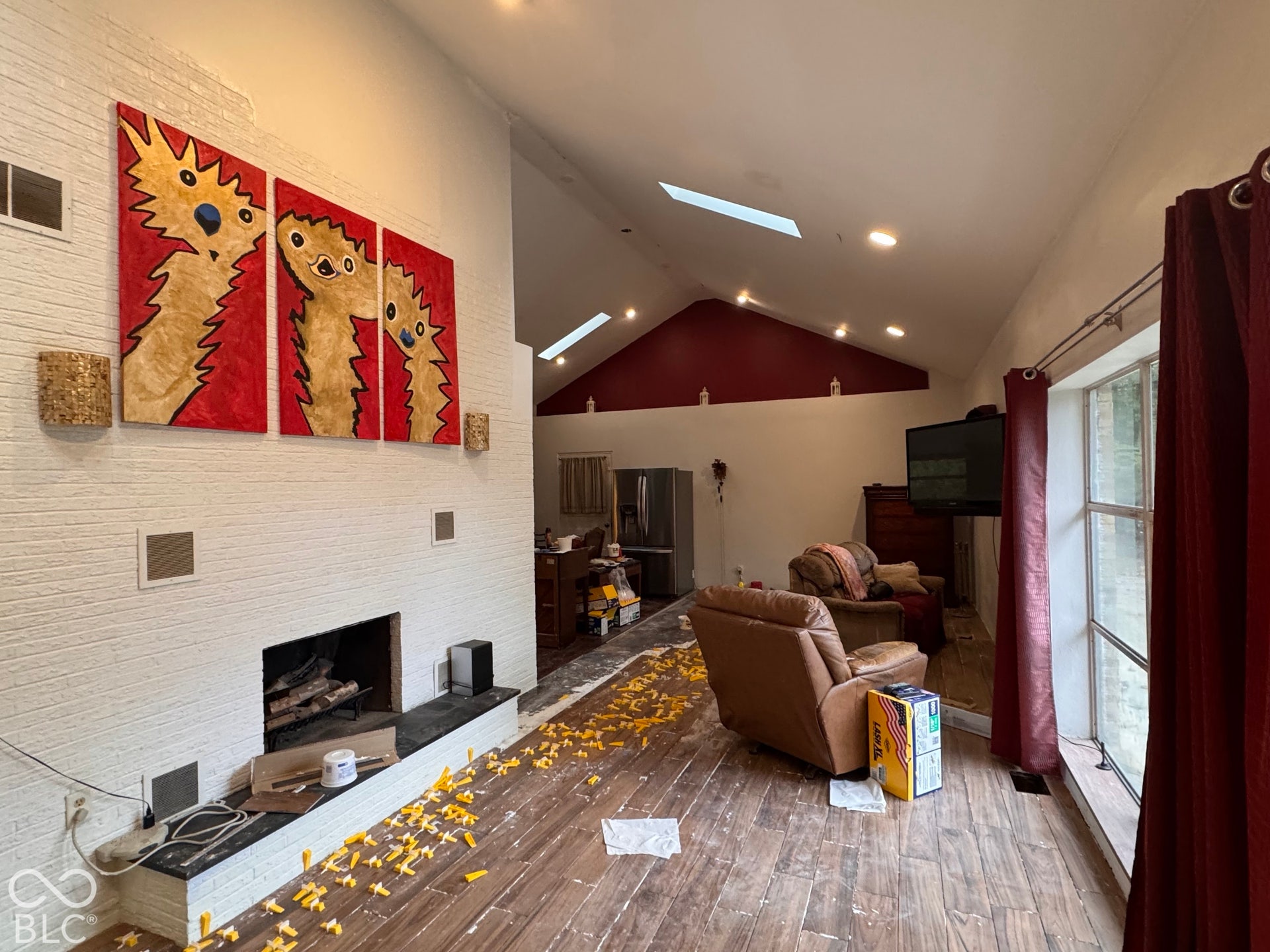Vaulted ceiling featuring skylights, new porcelain hardwood flooring being installed