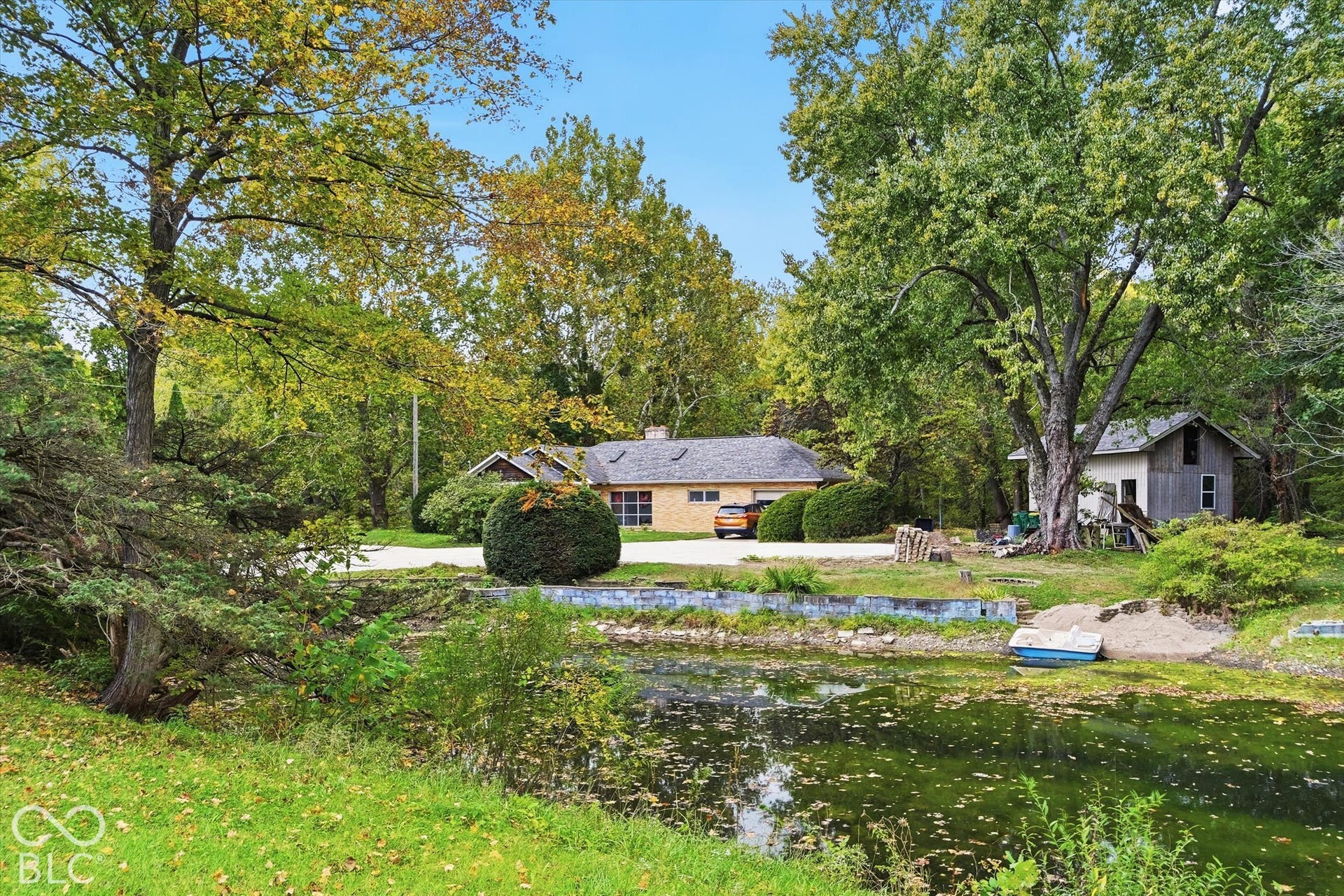 Waterfront property featuring a residential structure with a brick exterior, and a 2 story storage barn, mature trees